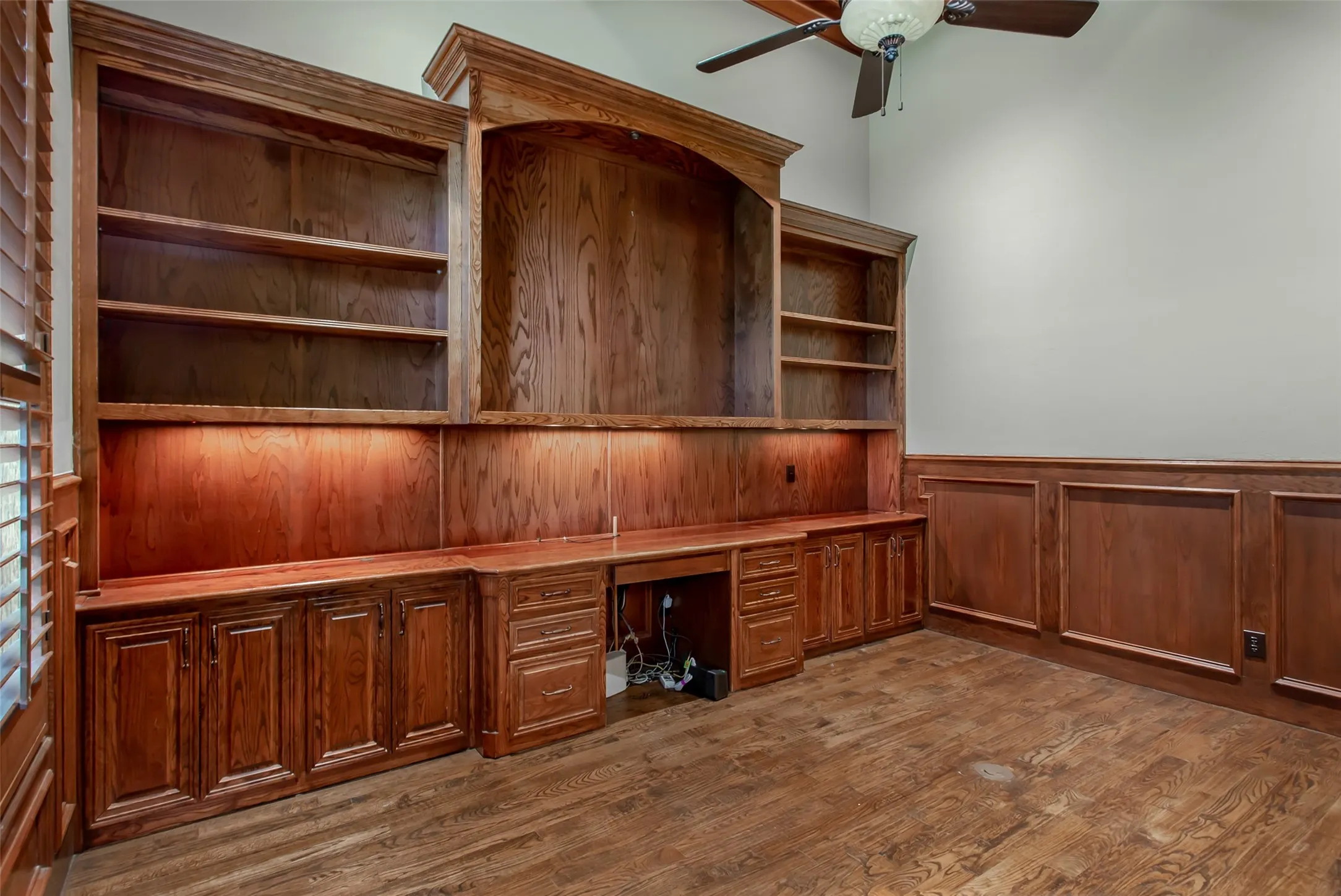 Custom built-in cabinetry, illuminated display shelving, and an expansive workspace create the perfect executive office or private library.