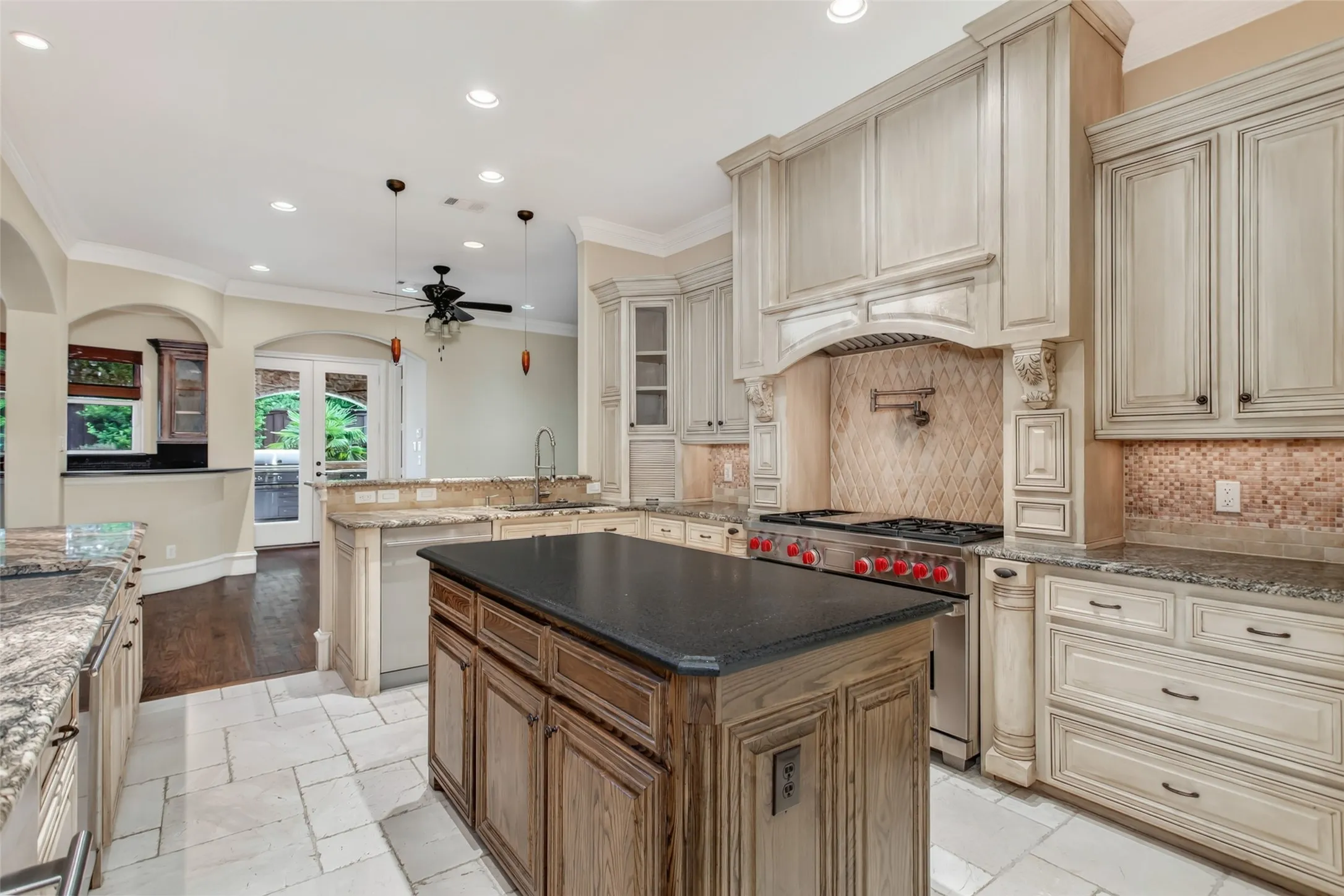The heart of the home features custom cabinetry, a commercial-grade Wolf gas range with pot filler, oversized center island, and generous prep space designed for everyday living and entertaining.