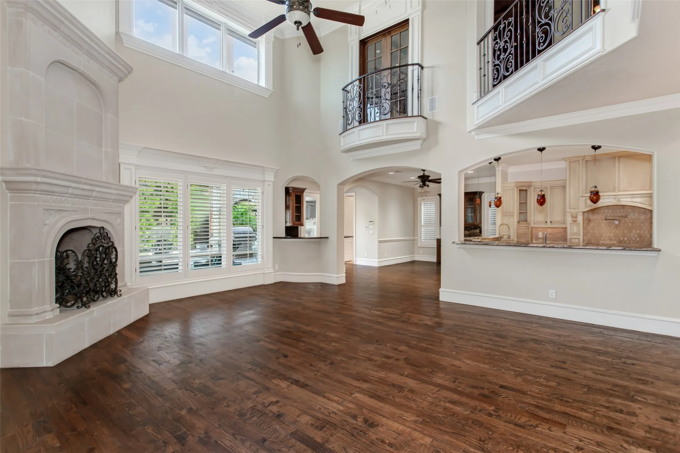 A stunning perspective of the home's open floor plan highlights the impressive second-story gallery, custom wrought-iron railings, extensive built-ins, and seamless flow from the grand foyer through the main living spaces.