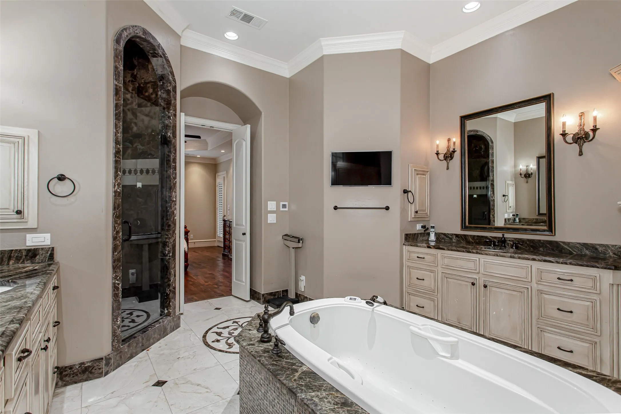 An exceptional spa retreat complete with a therapeutic jetted tub, oversized walk-in shower with dramatic marble surround, dual vanities, extensive storage, and refined designer finishes throughout.