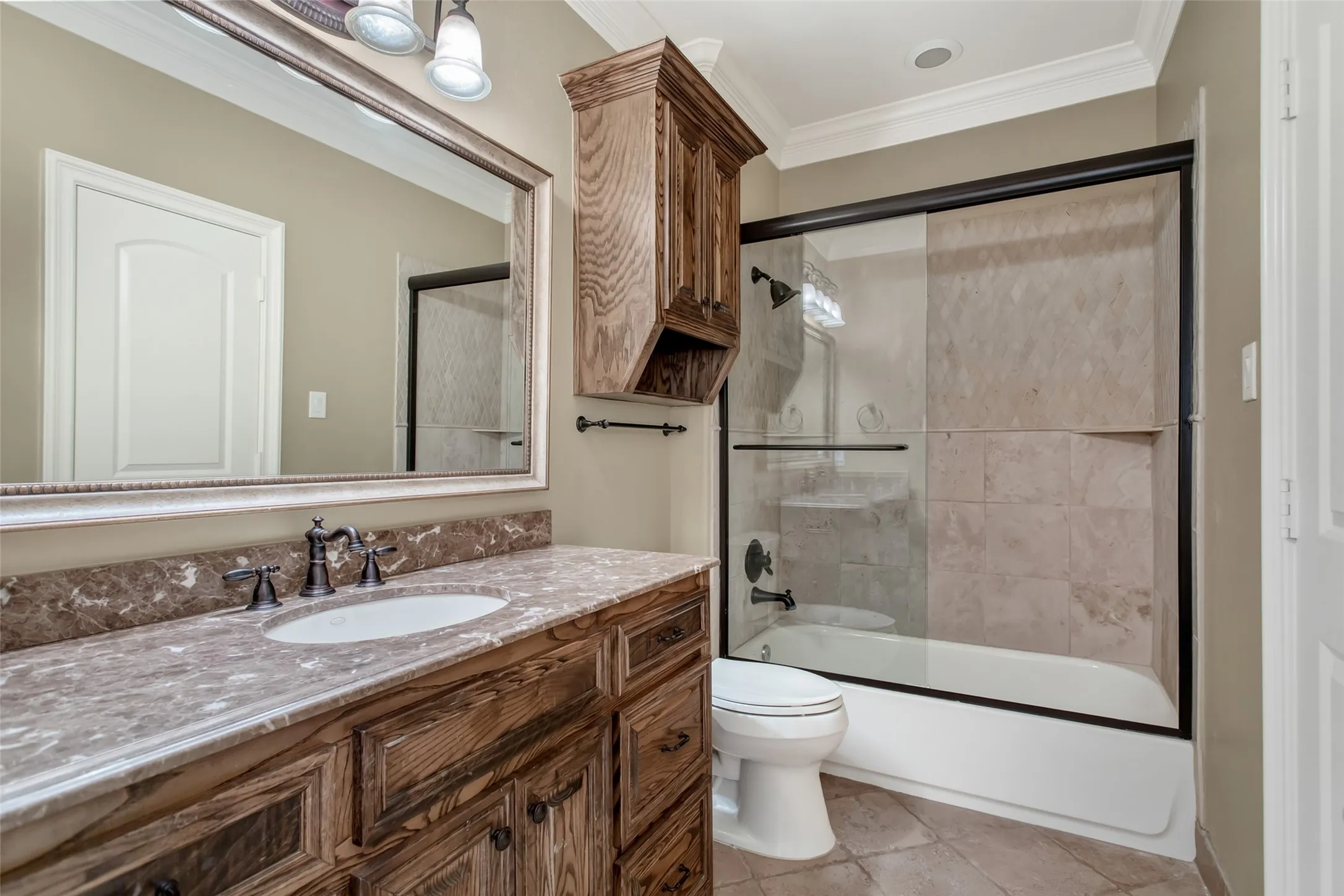 the private ensuite bath features granite countertops, custom wood cabinetry, and a beautifully finished tub/shower combination with frameless glass enclosure and designer tile surround.