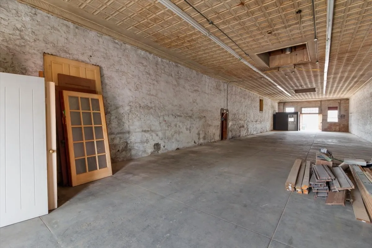 Expansive interior space featuring a patterned ceiling, concrete flooring, and exposed brick walls