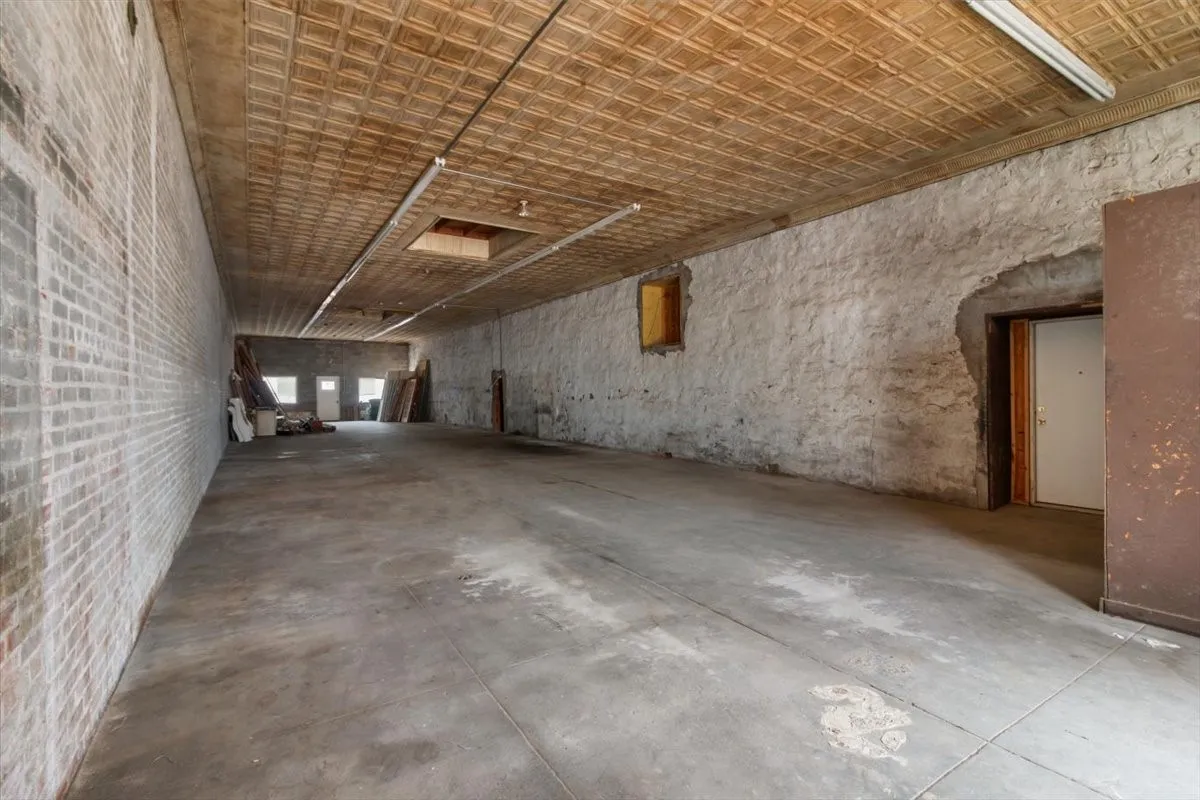 Spacious interior featuring a concrete floor, exposed brick wall, and a textured ceiling