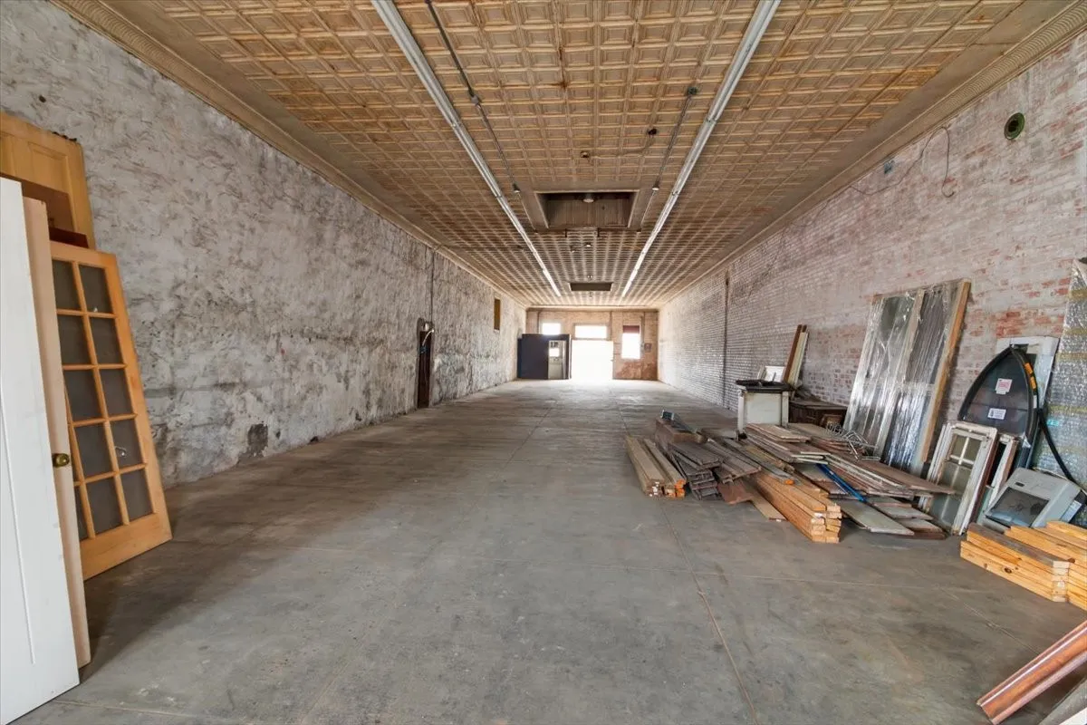 Spacious commercial interior featuring a pressed tin ceiling and exposed brick walls