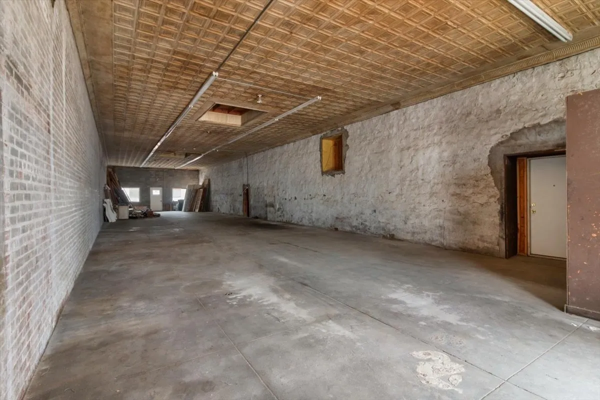 Expansive open-concept interior featuring a textured ceiling, exposed brick wall, and concrete flooring
