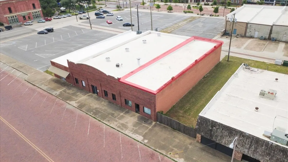 Commercial building with a red brick facade and a flat roof, featuring multiple storefront entrances