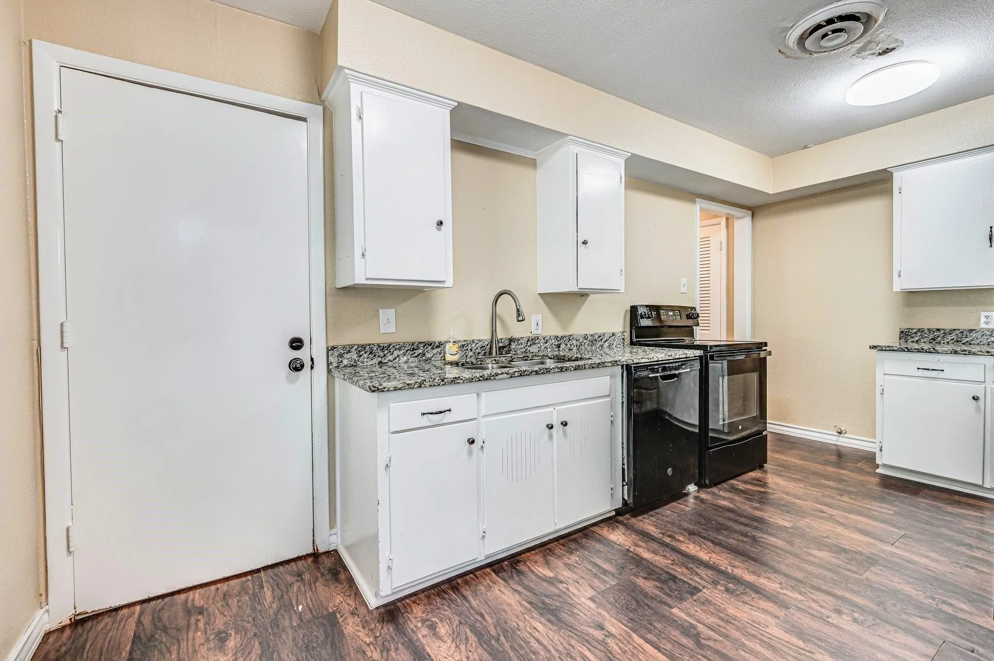 Kitchen featuring wood-finish flooring, white cabinetry, granite-style countertops, and a stainless steel sink with a gooseneck faucet