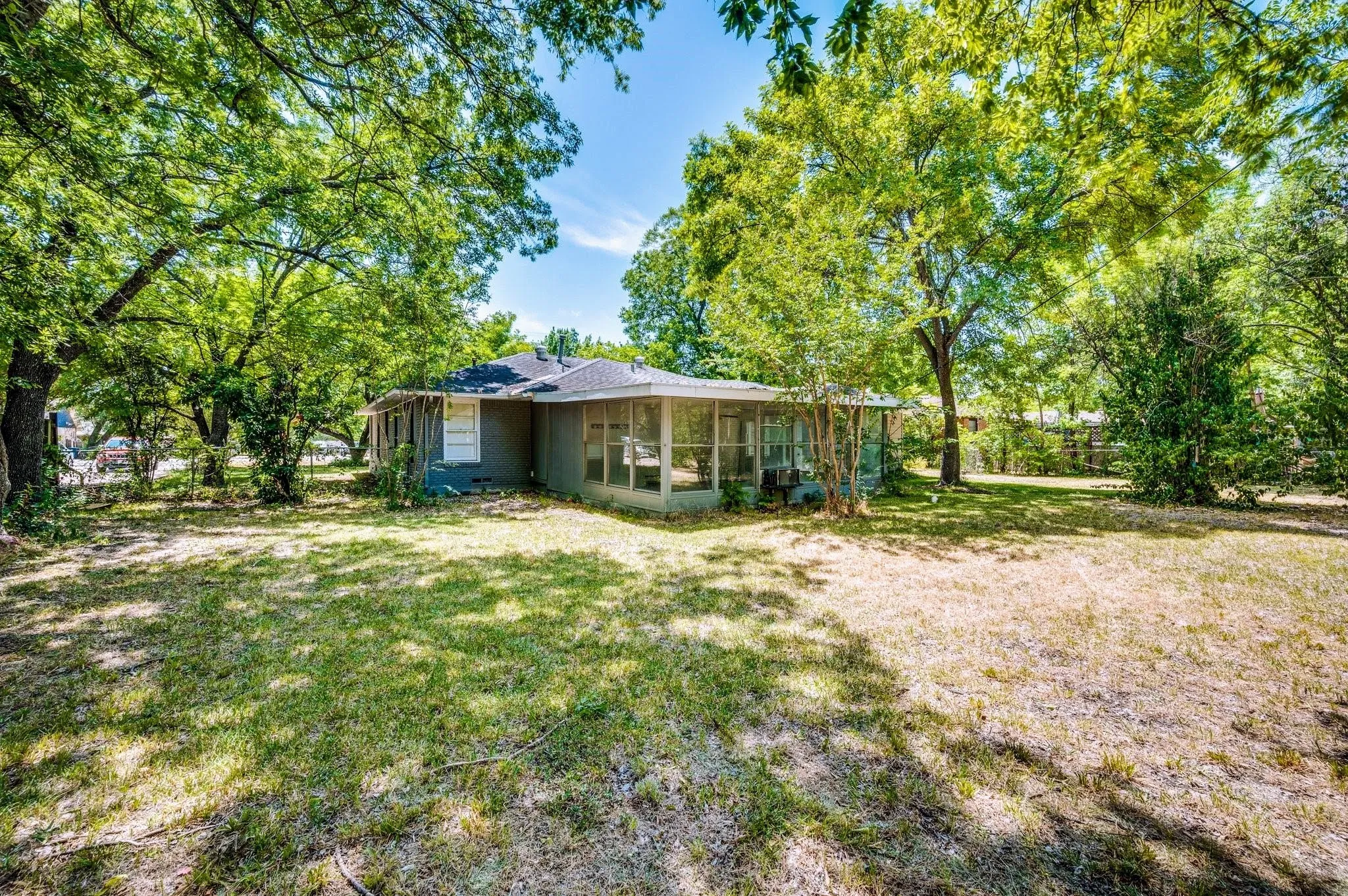 Expansive exterior featuring a screened porch, a pitched roofline, and mature trees providing natural shade