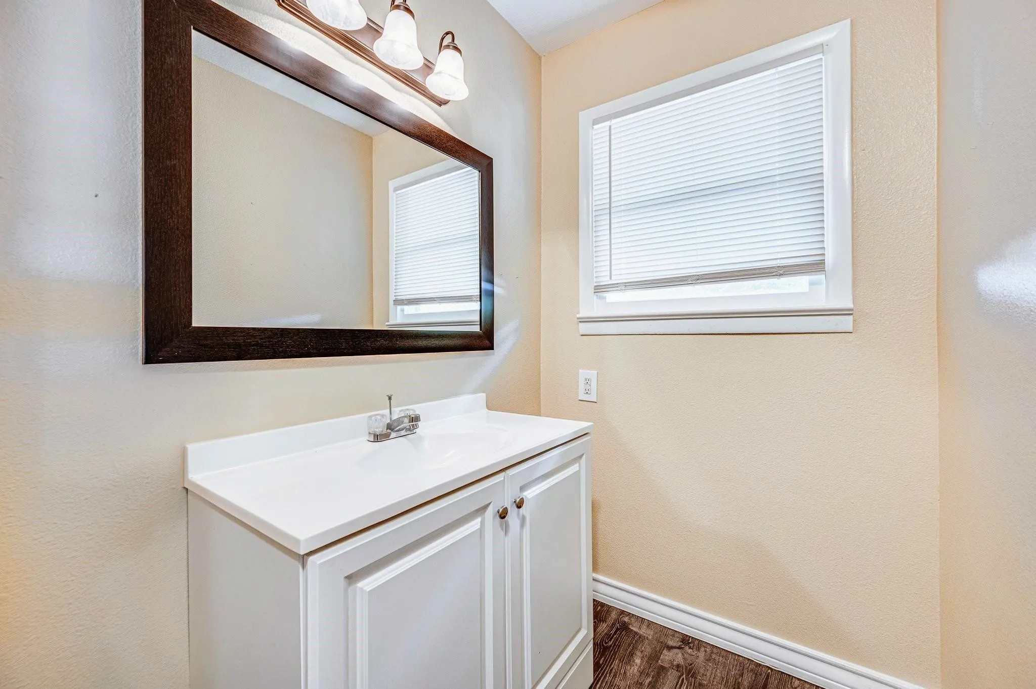 Bathroom vanity with integrated sink, chrome faucet, and white cabinetry