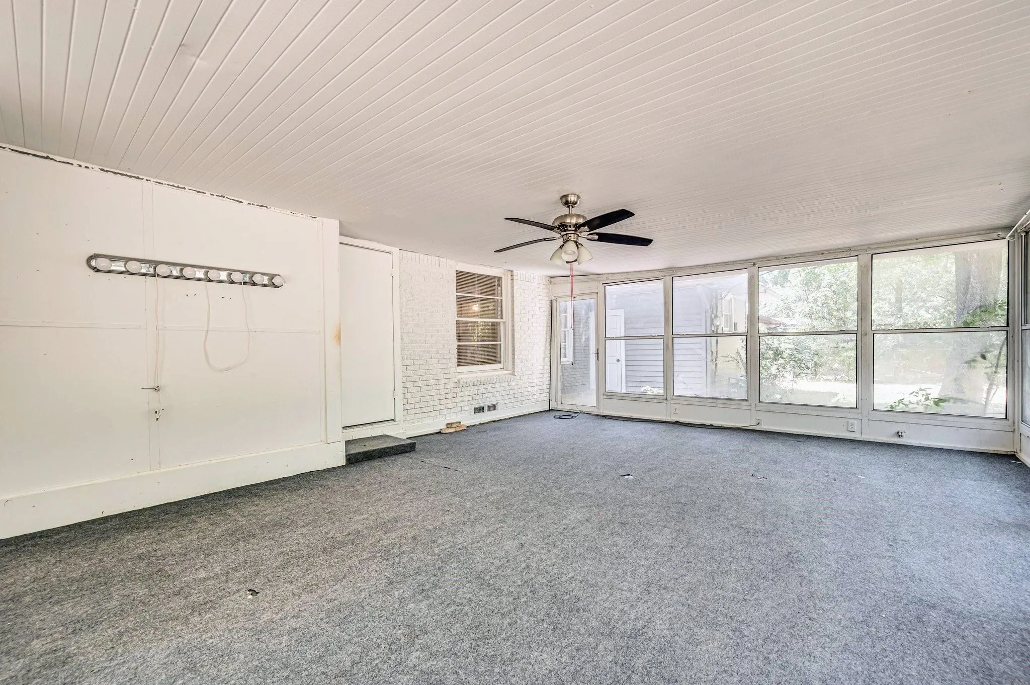 Spacious room featuring a ceiling fan, white paneled ceiling, and light gray wall-to-wall carpeting