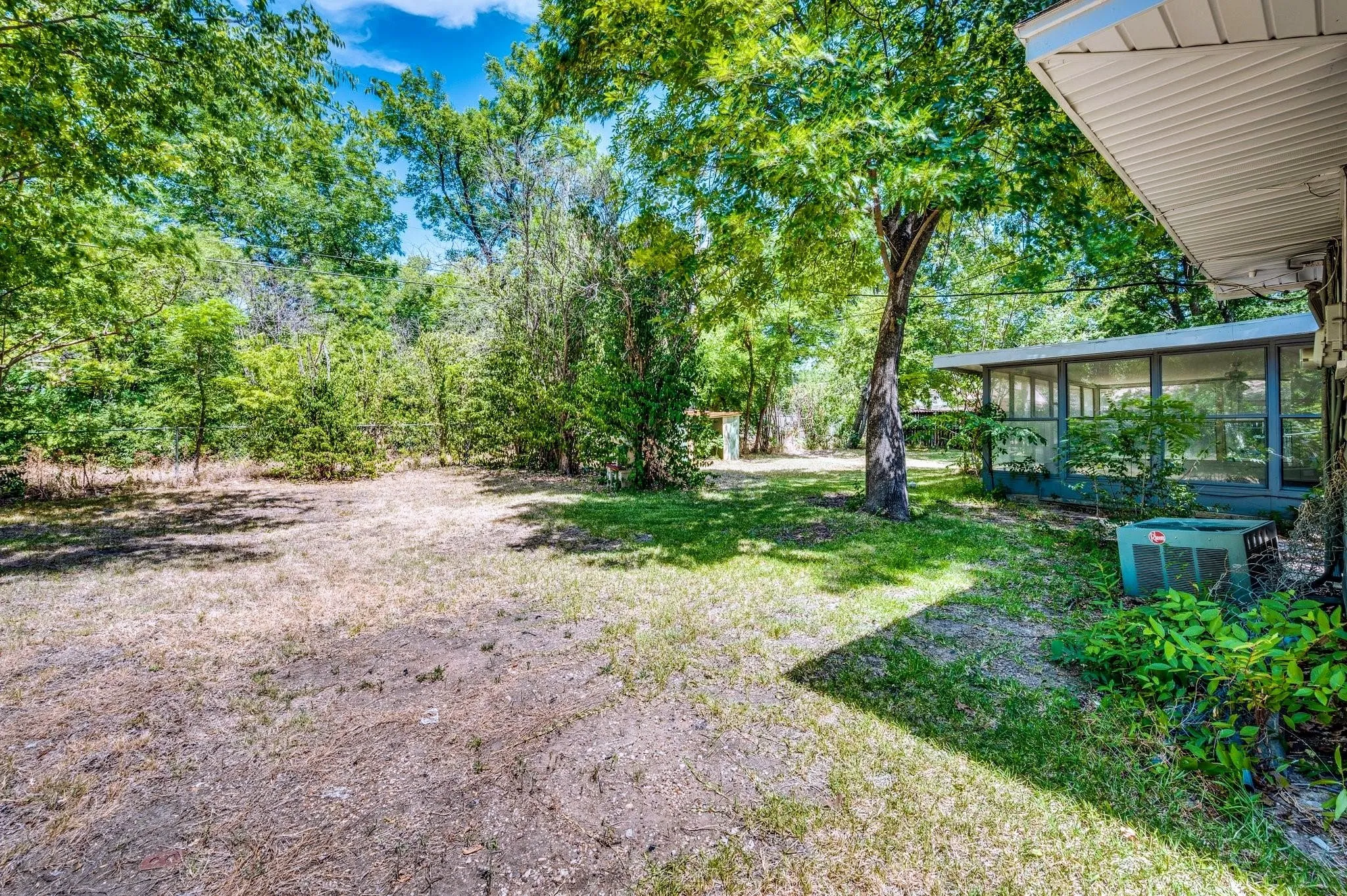 Expansive rear yard featuring a partial sunroom structure