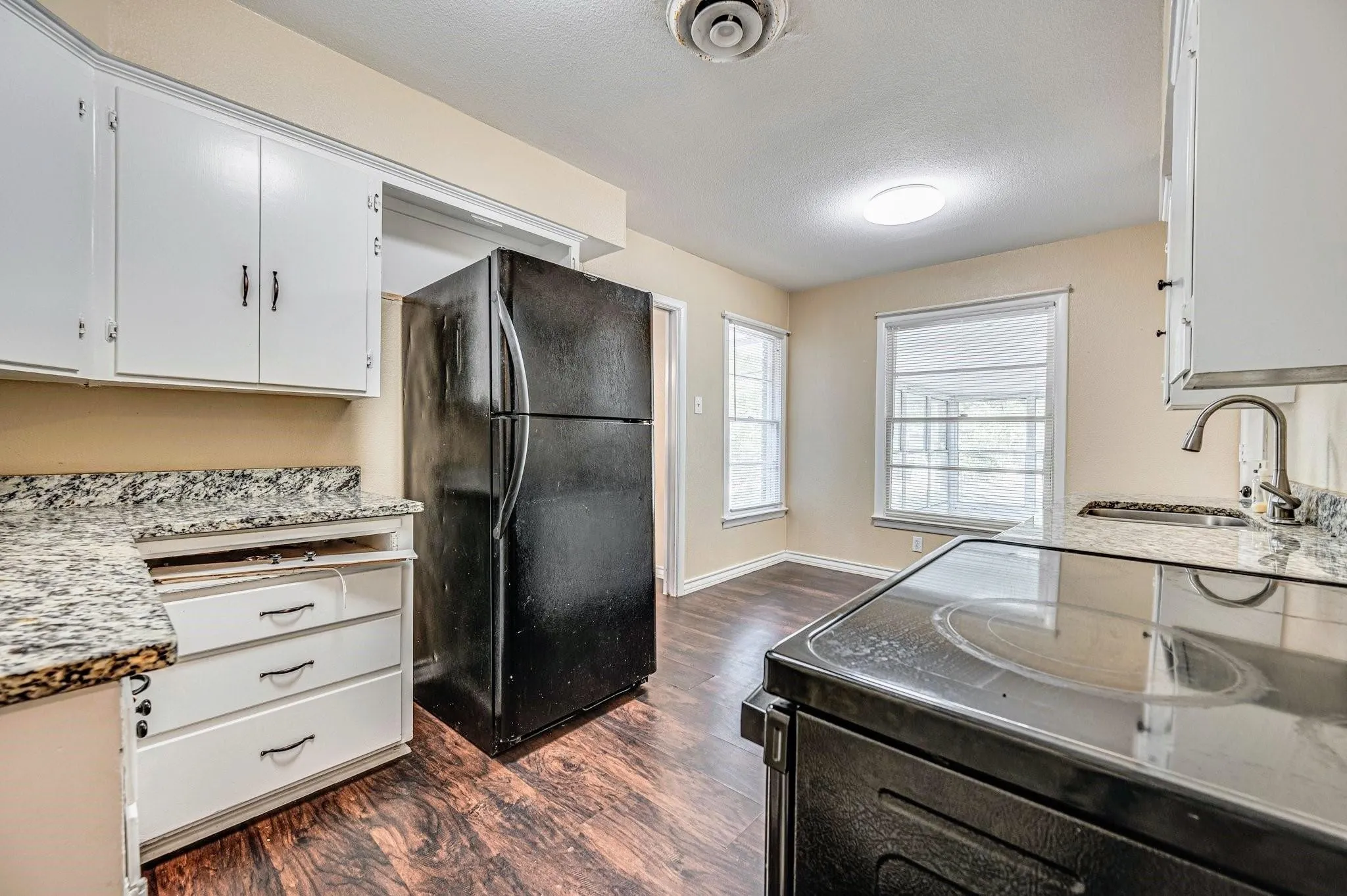 Kitchen featuring white cabinetry, granite-style countertops, wood-finish flooring, a stainless steel sink with a gooseneck faucet, and an electric range
