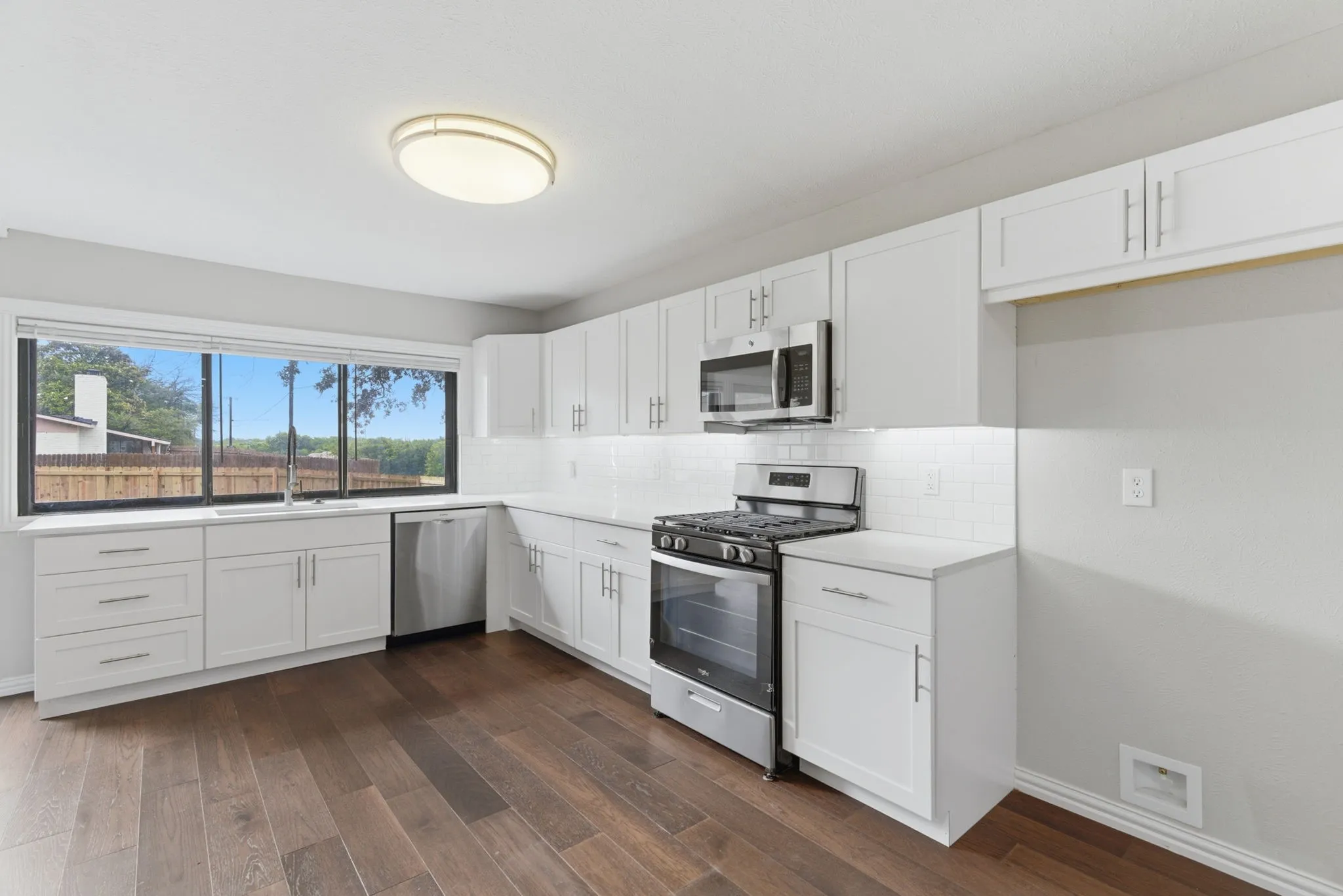 Modern kitchen featuring white shaker cabinetry, stainless steel appliances, white countertops, and a subway tile backsplash