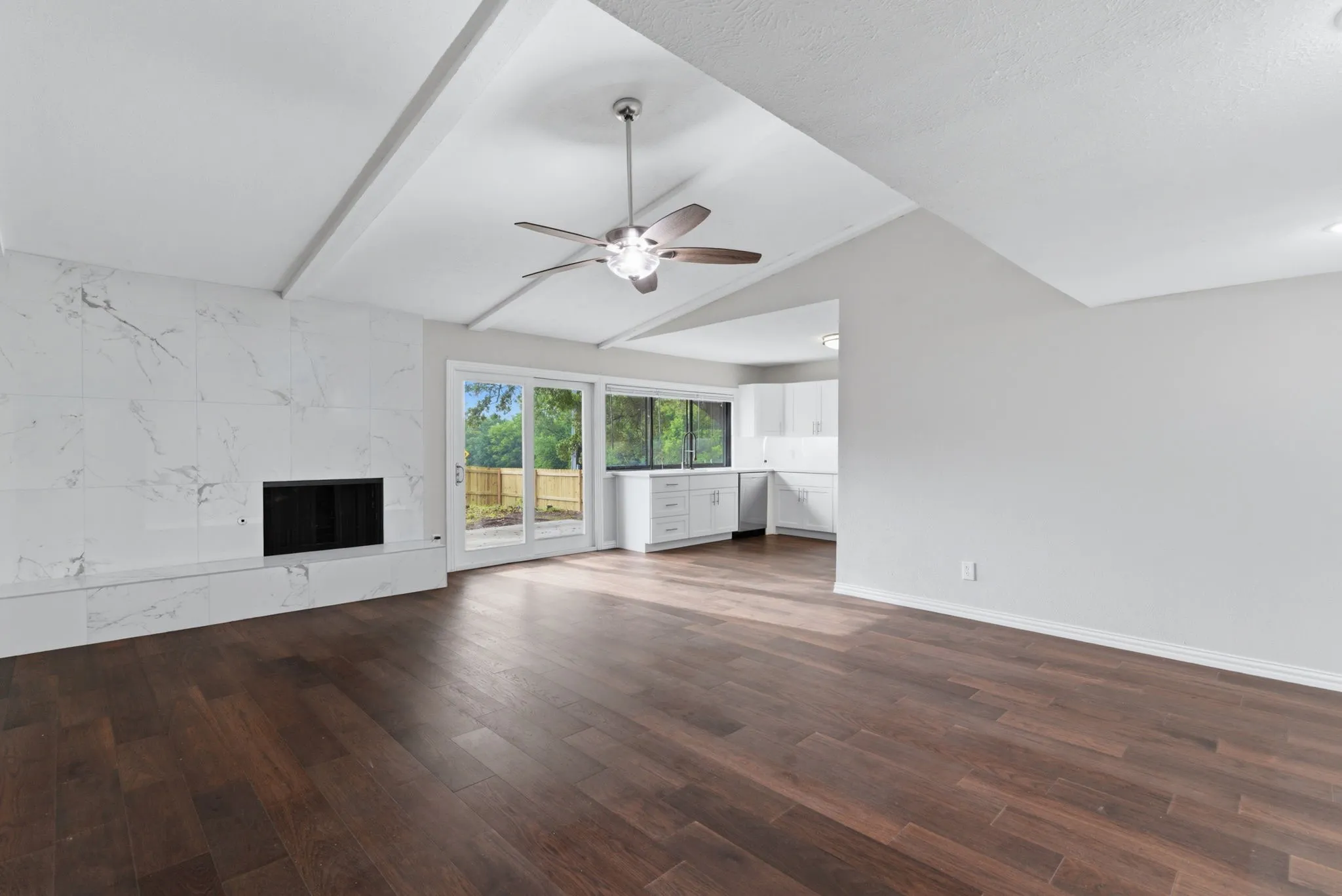 Spacious interior featuring wood-finish flooring, a vaulted ceiling with exposed beams, and a ceiling fan