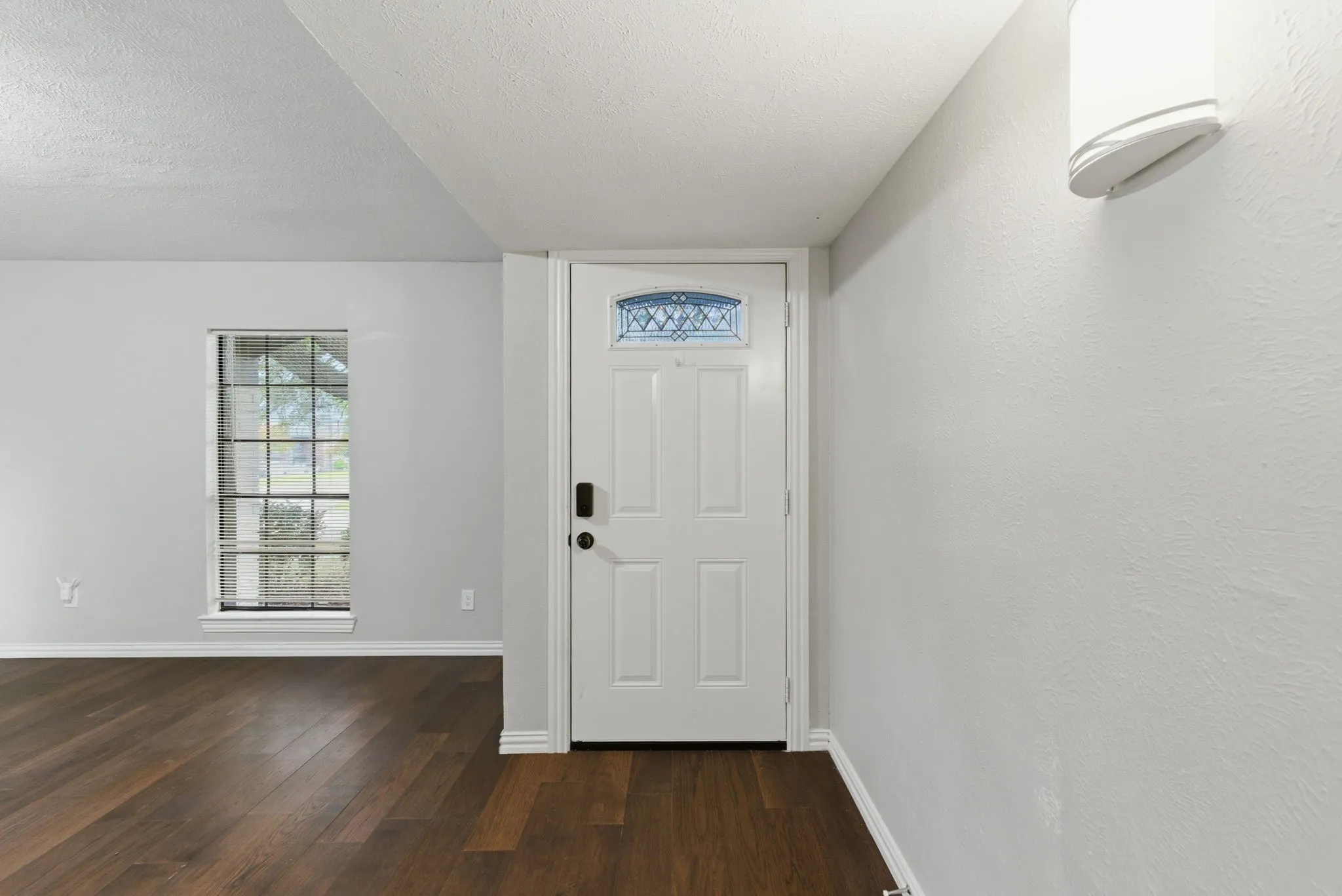 Entryway featuring a paneled door with decorative glass, wood-finish flooring, and light gray wall paint