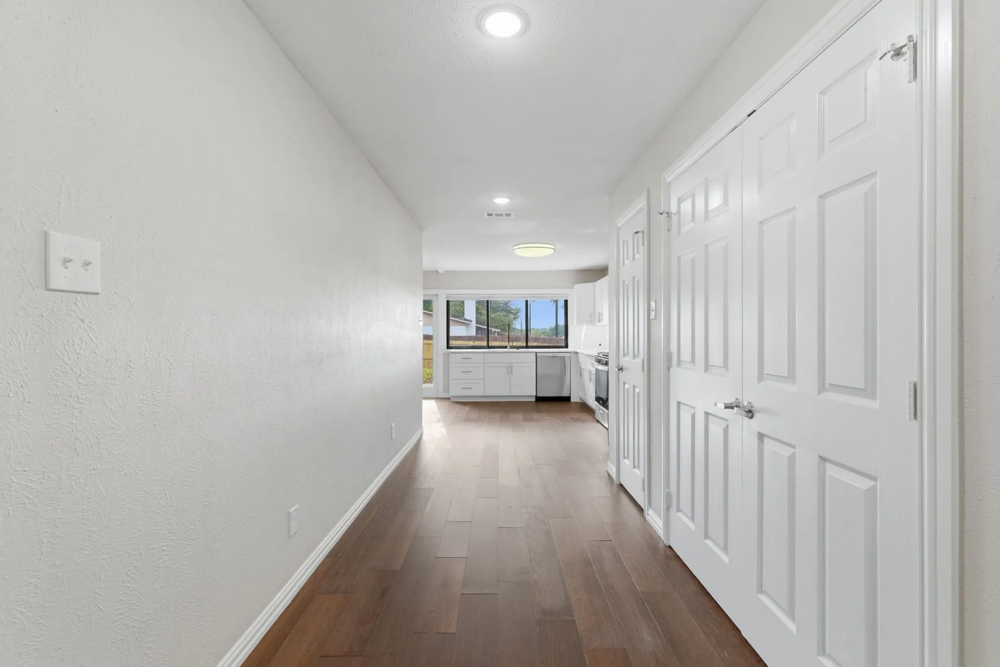 Hallway with wood-finish flooring, recessed lighting, and white paneled doors