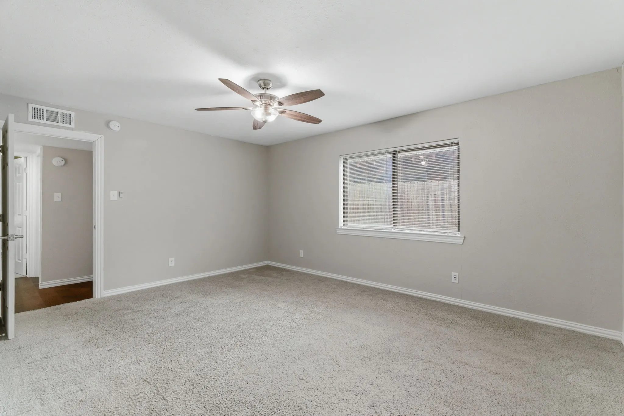 Carpeted room featuring light gray walls, white trim, a ceiling fan with light fixture, and a window with blinds