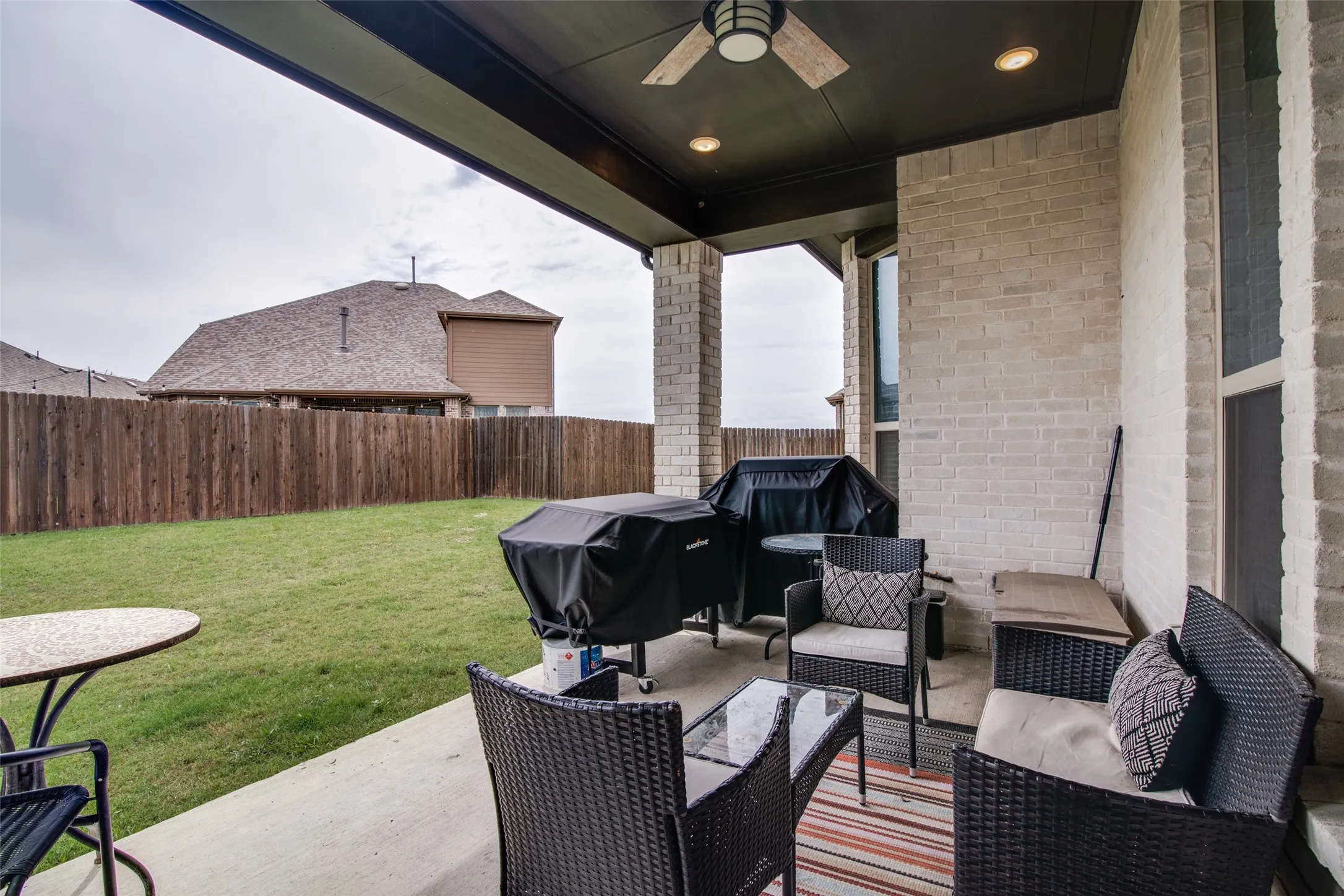 Covered patio with a concrete surface, featuring an exterior ceiling fan with integrated lighting, recessed lighting, and light-colored brick walls