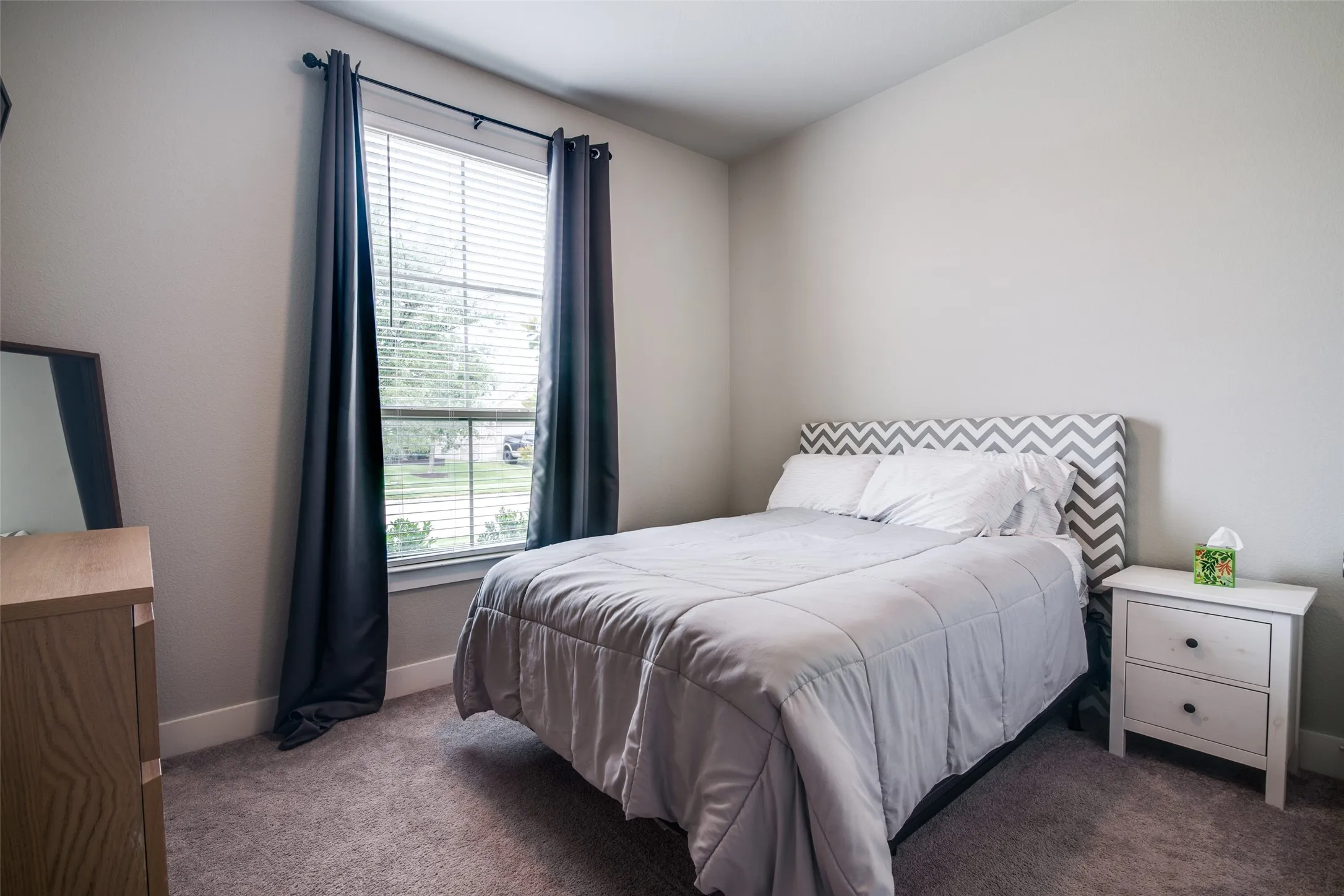 Carpeted room featuring light gray walls, a single window with blinds, and white baseboards