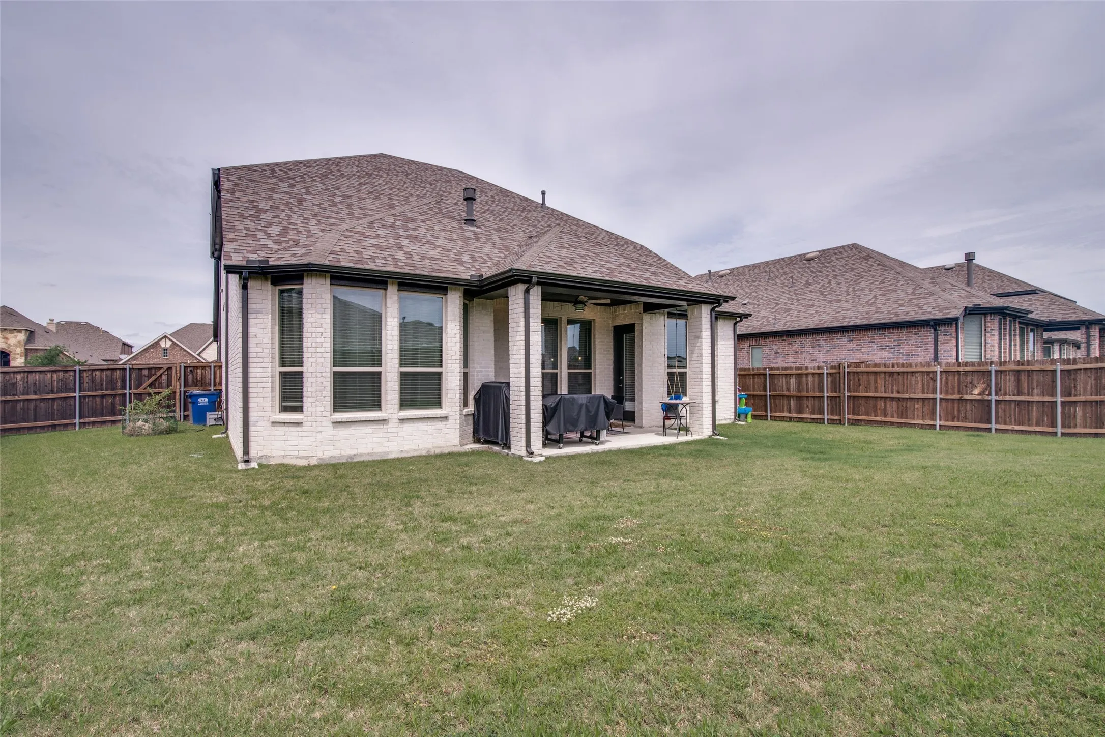 Expansive green lawn with a white brick exterior