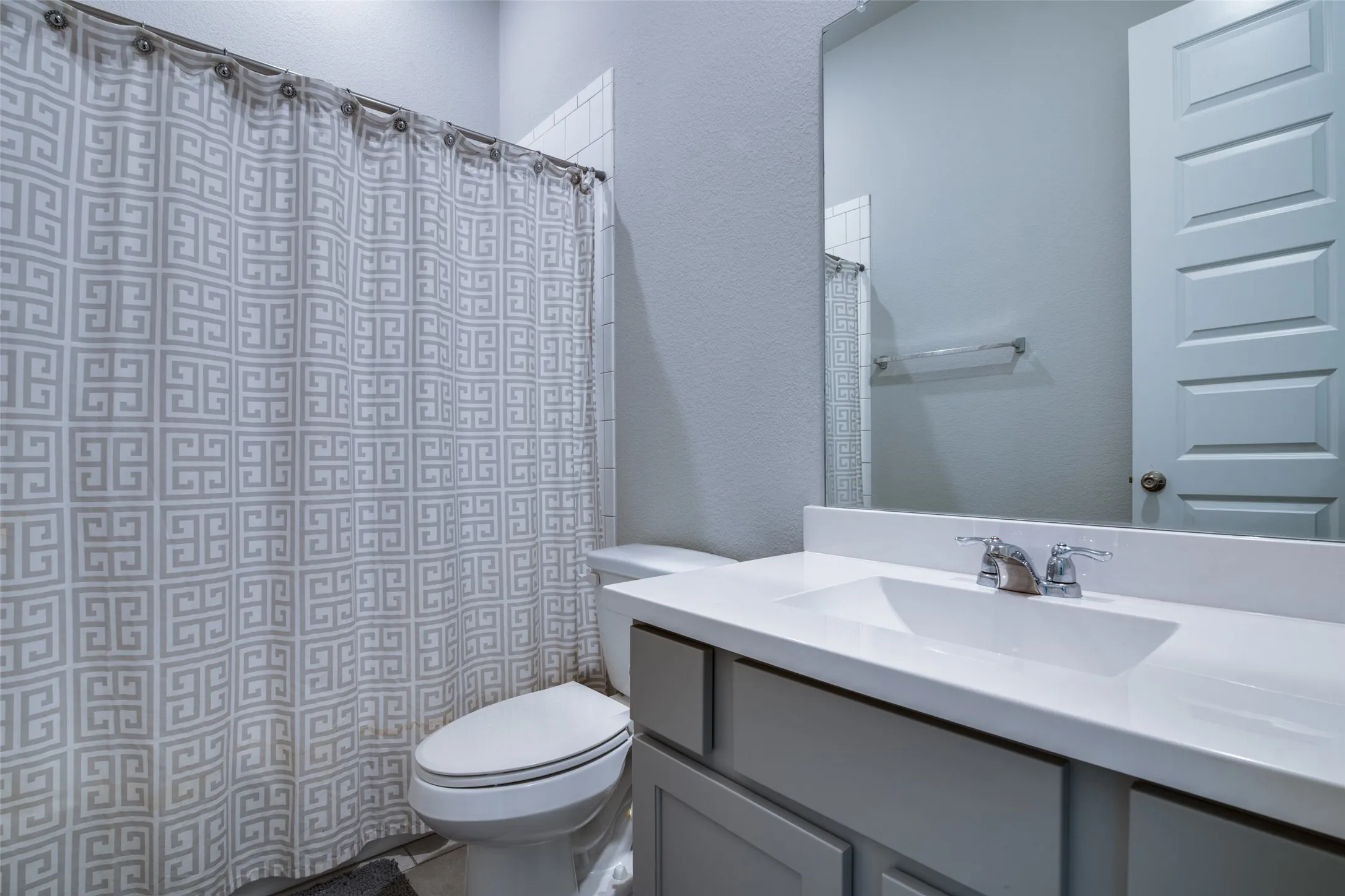 Bathroom featuring a single vanity with an integrated sink, polished chrome faucet, and a large wall-mounted mirror