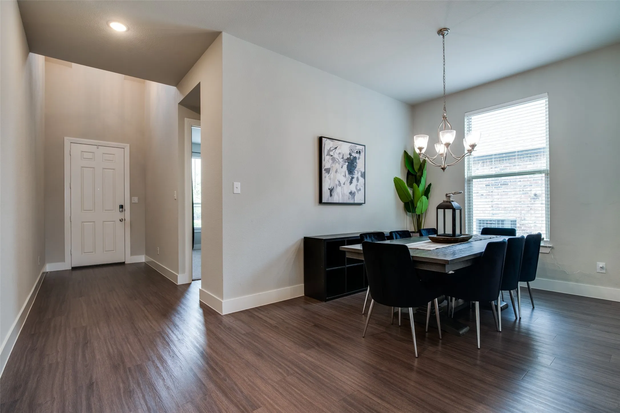Entryway and dining area featuring wood-finish flooring, neutral wall tones, and a paneled entry door