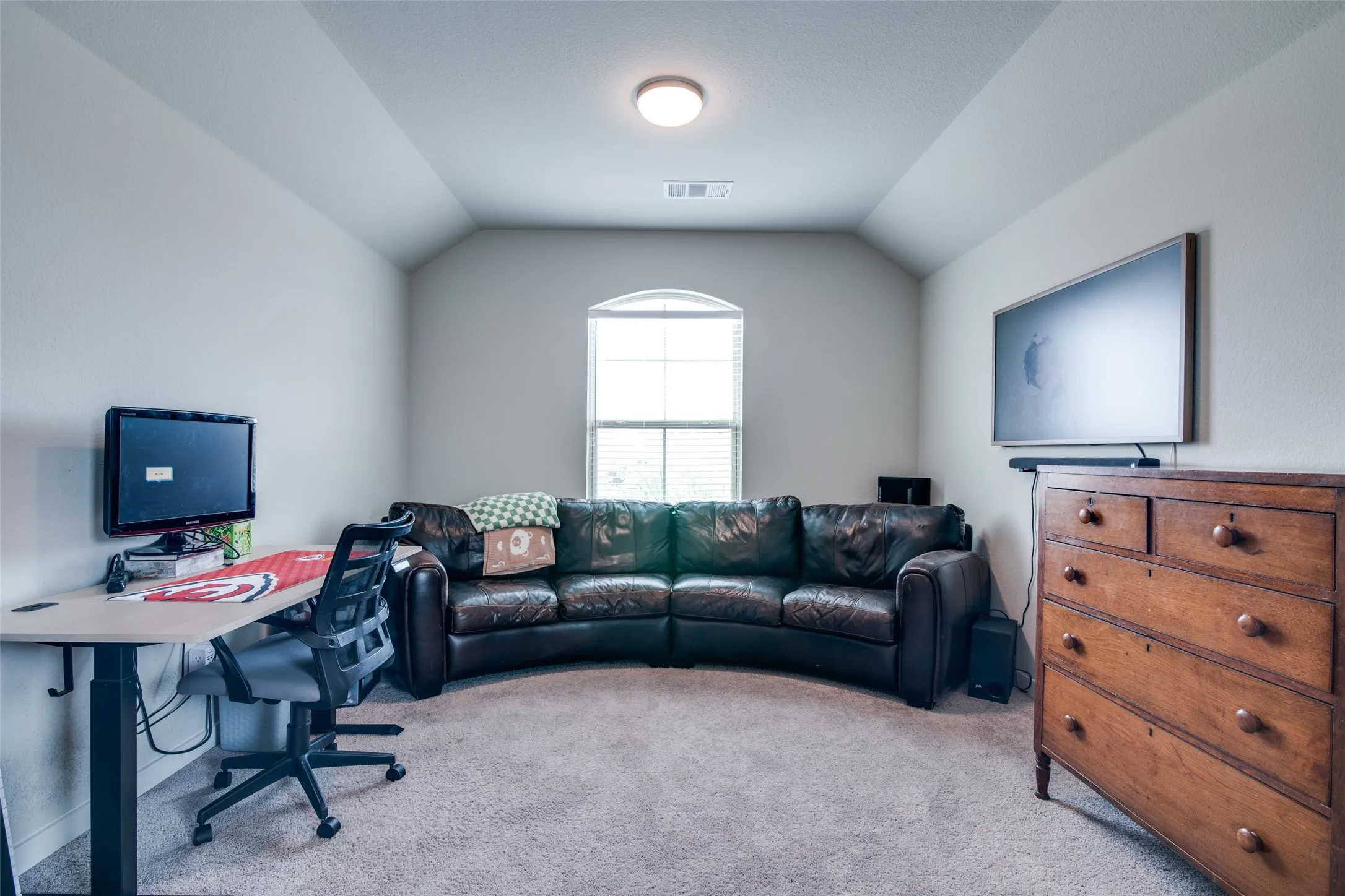 Carpeted room featuring a ceiling-mounted light fixture, an arched window with blinds, and sloped ceiling details