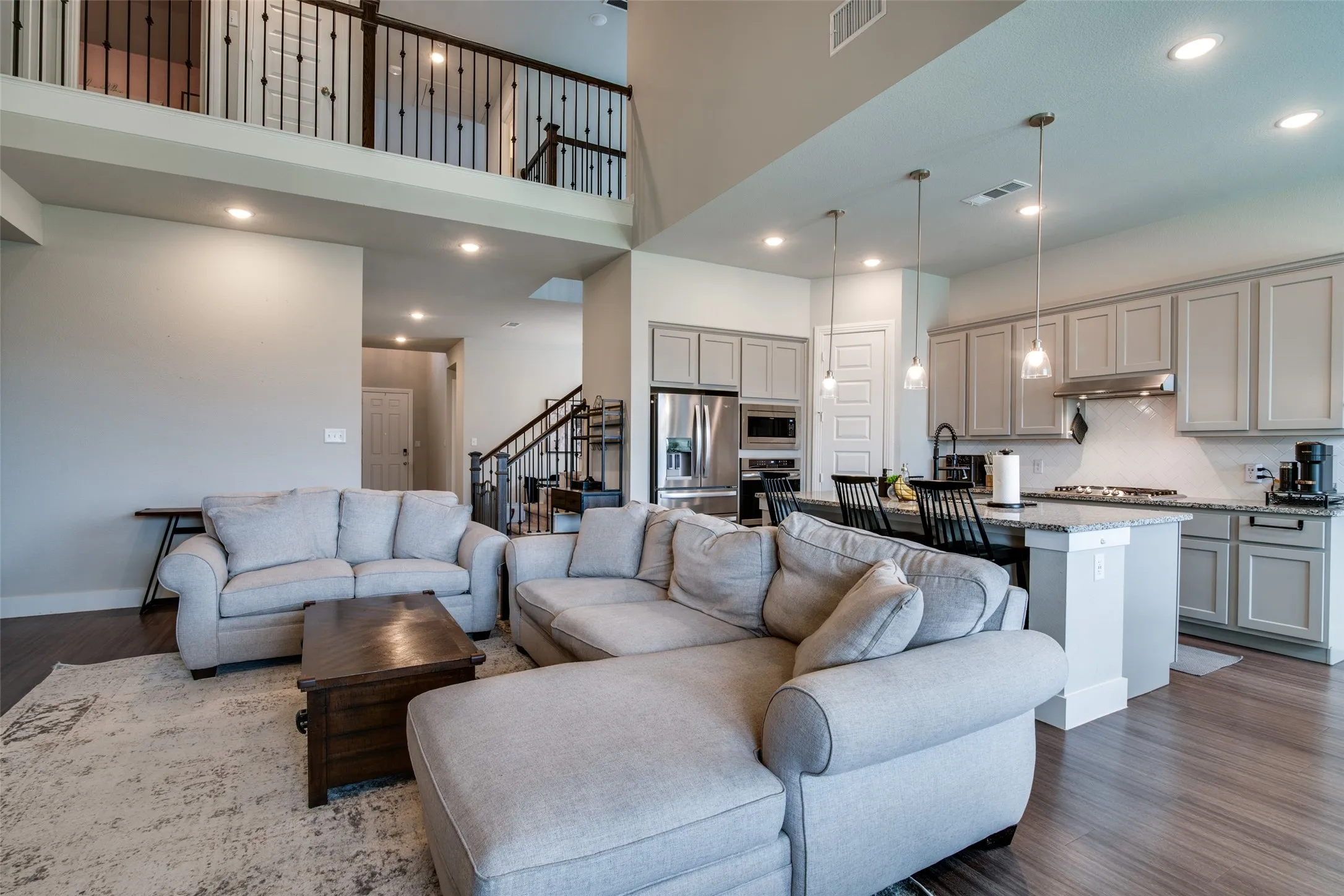 Open-concept living space featuring wood-finish flooring, a two-story ceiling, and recessed lighting