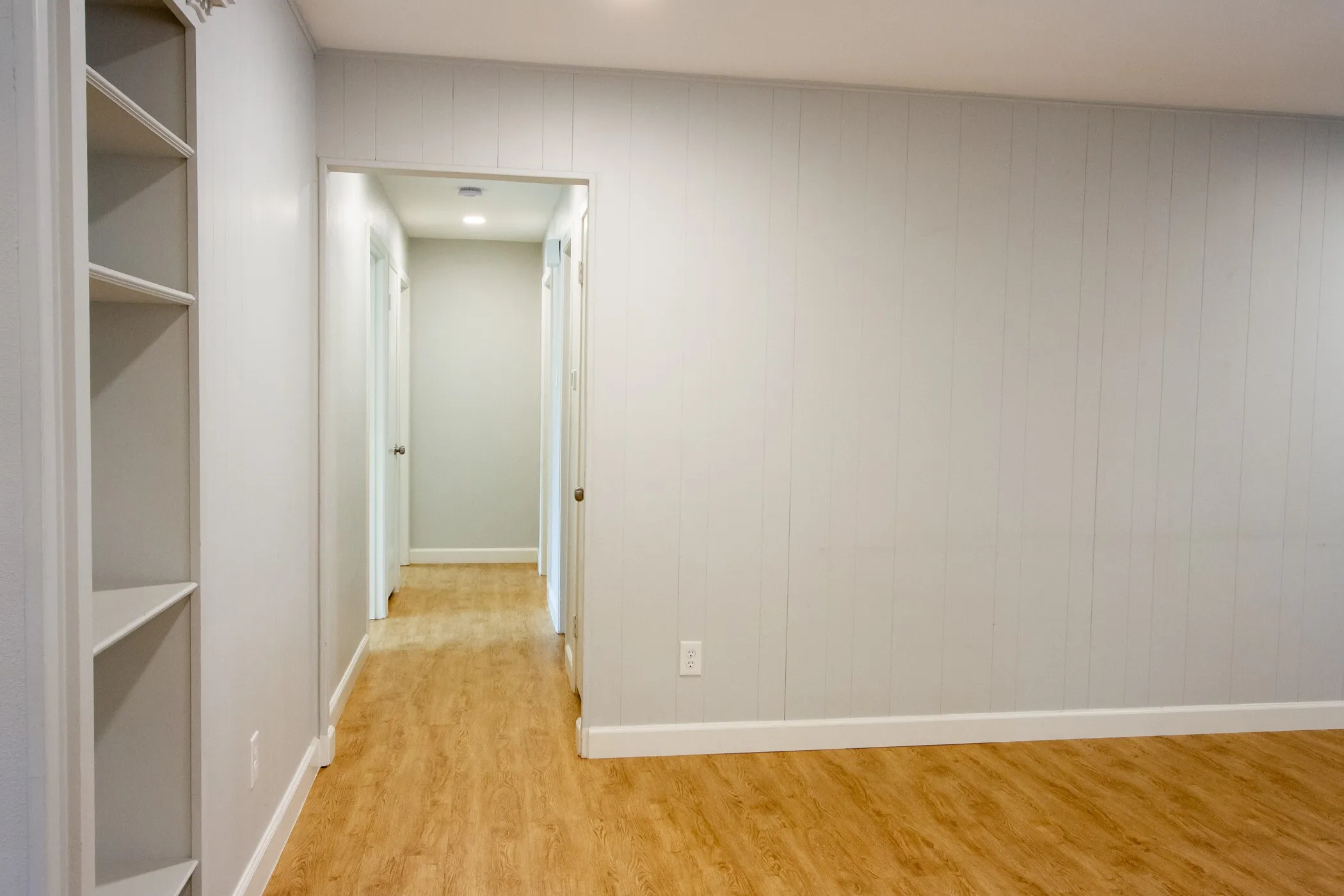 Corridor with light wood-type flooring and baseboards