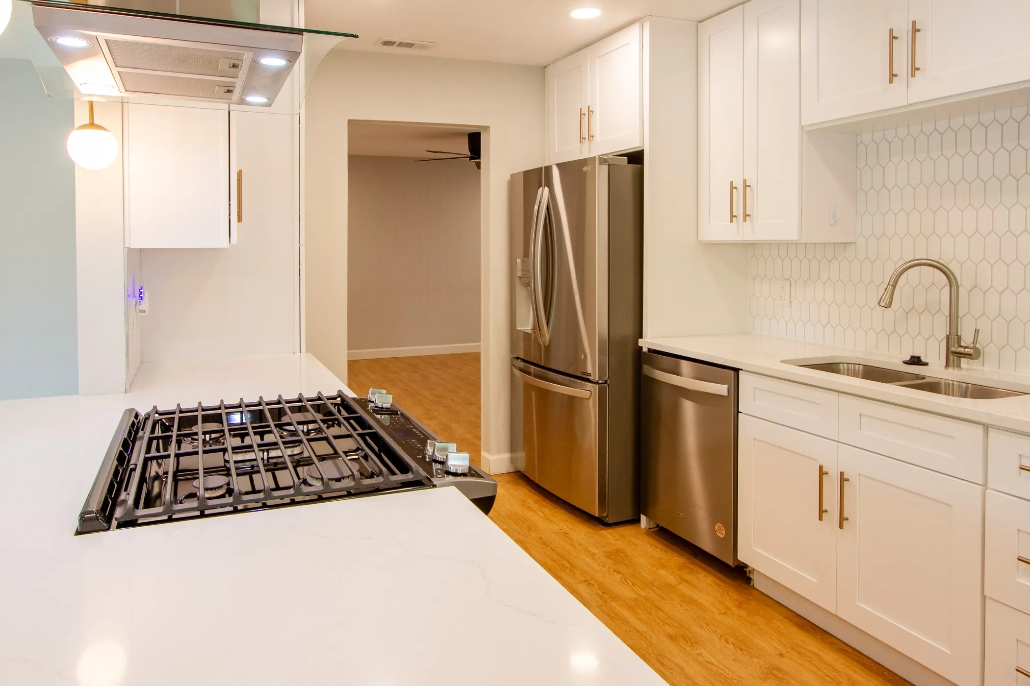 Kitchen featuring stainless steel appliances, a sink, light wood-style floors, decorative backsplash, and white cabinets