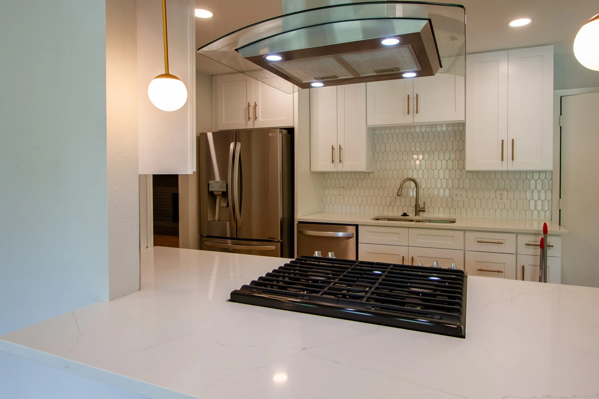 Kitchen featuring stainless steel appliances, a sink, range hood, tasteful backsplash, and white cabinets
