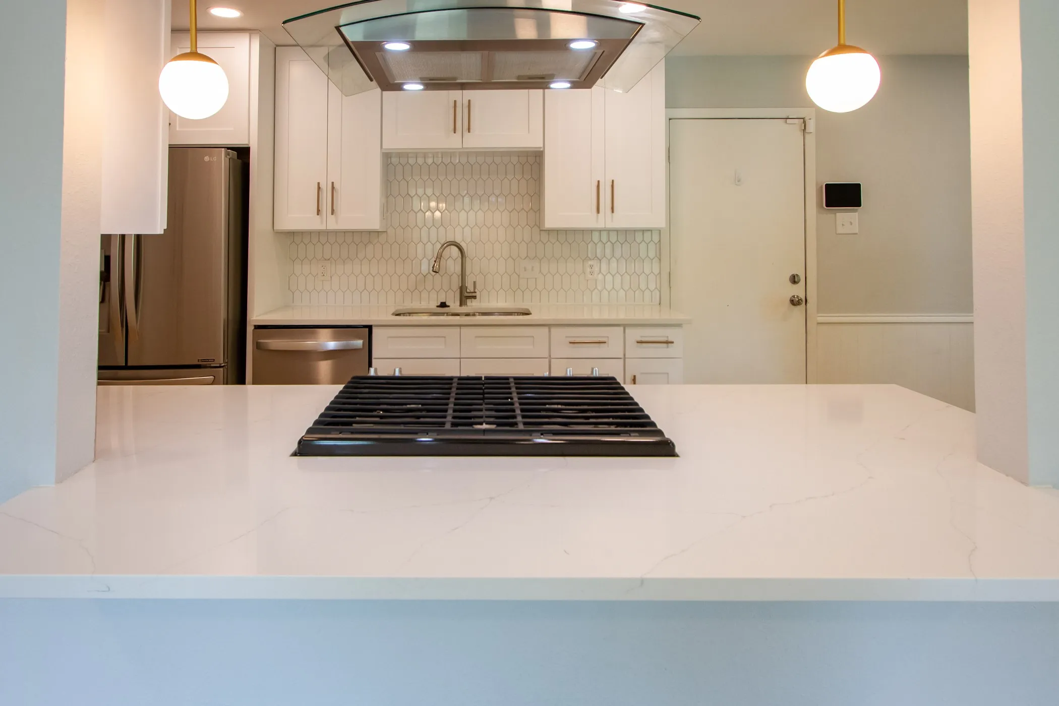 Kitchen with a sink, appliances with stainless steel finishes, ventilation hood, tasteful backsplash, and white cabinetry