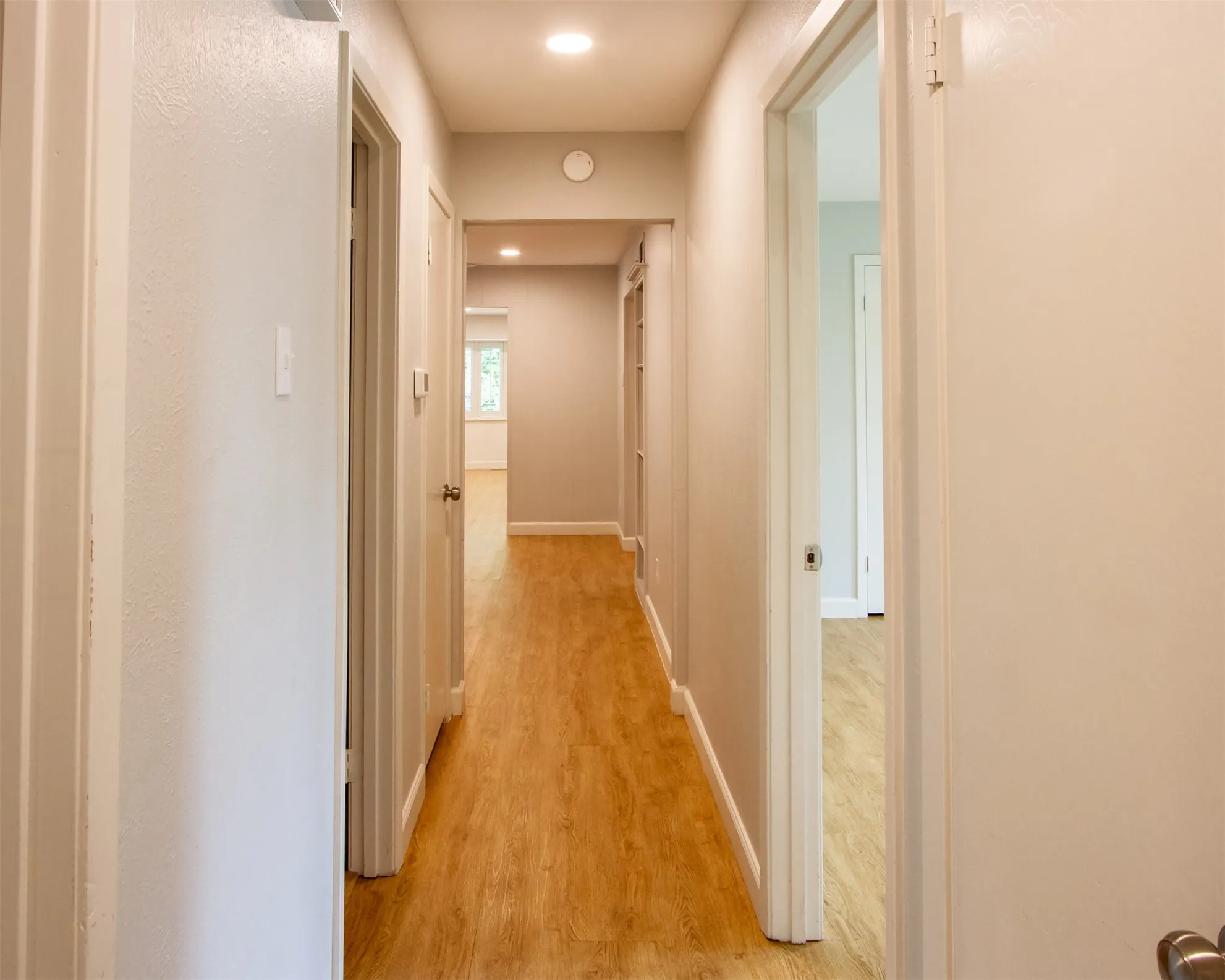 Corridor with light wood-style flooring, baseboards, and recessed lighting