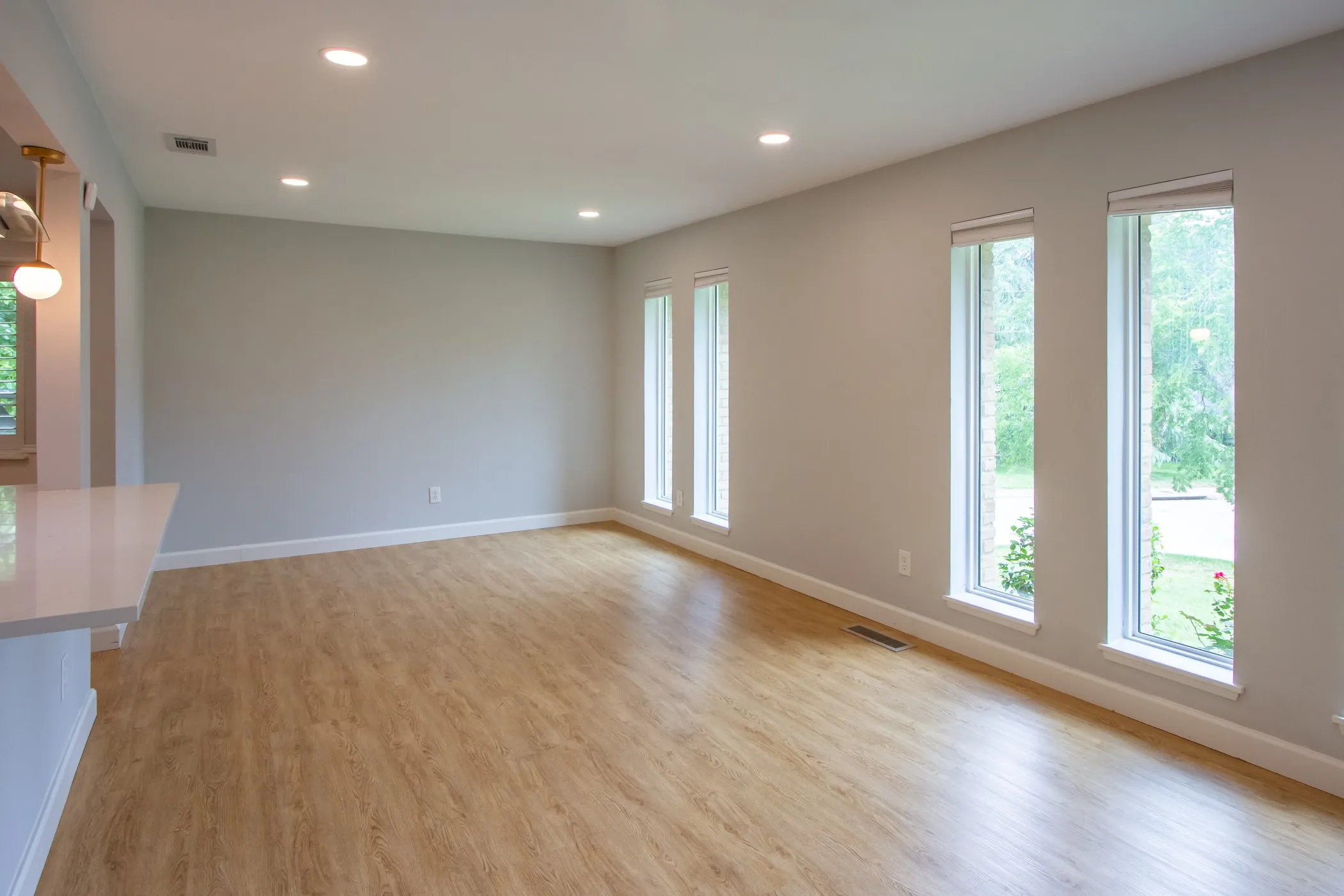 Unfurnished living room featuring plenty of natural light, recessed lighting, light wood finished floors, and baseboards