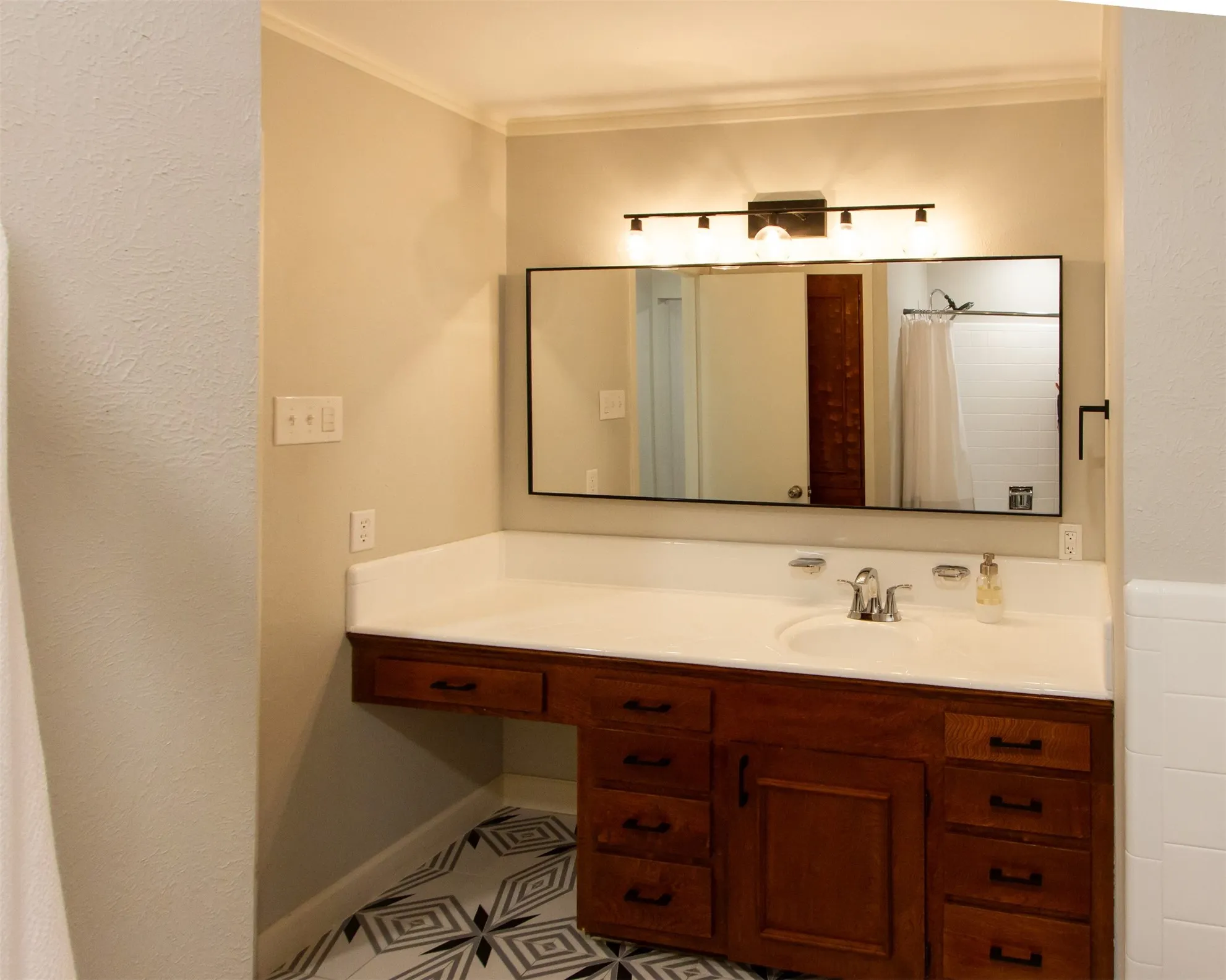 Bathroom with vanity, crown molding, baseboards, and tile patterned flooring