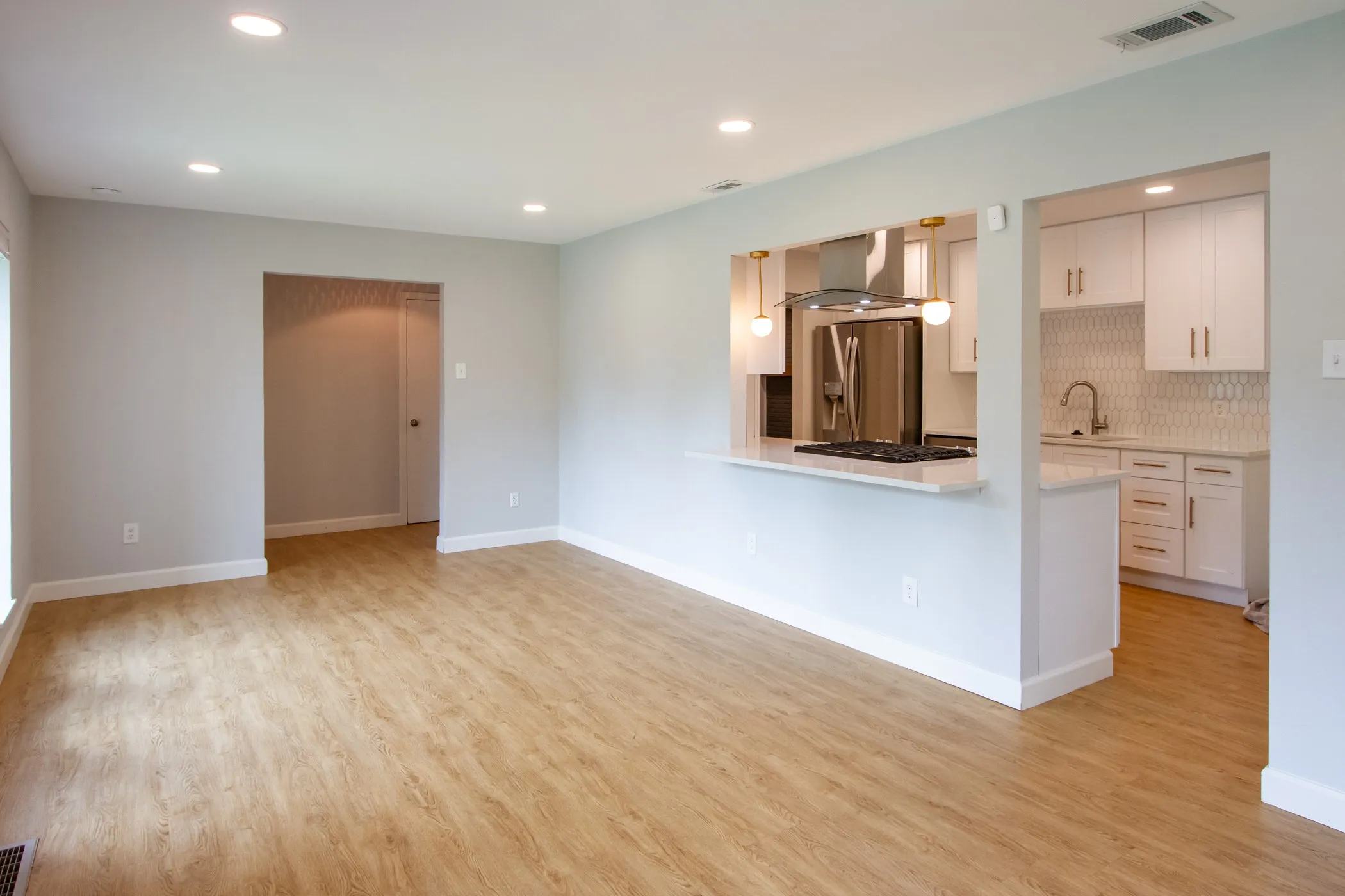 Unfurnished living room with light wood finished floors, a sink, recessed lighting, and baseboards