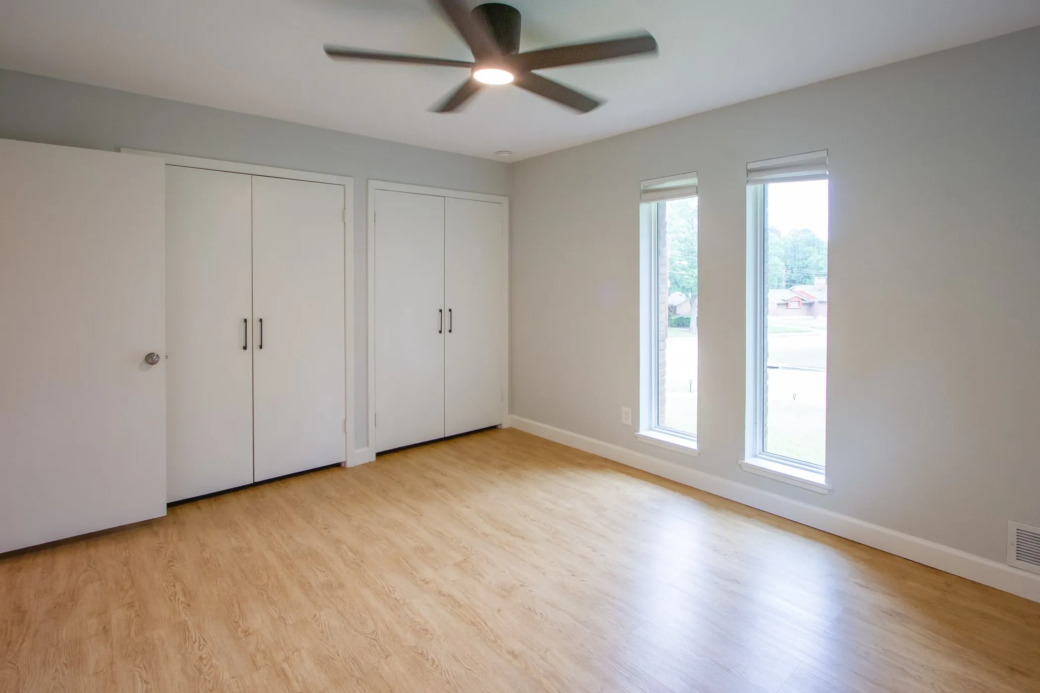 Unfurnished bedroom with two closets, light wood-type flooring, baseboards, and ceiling fan