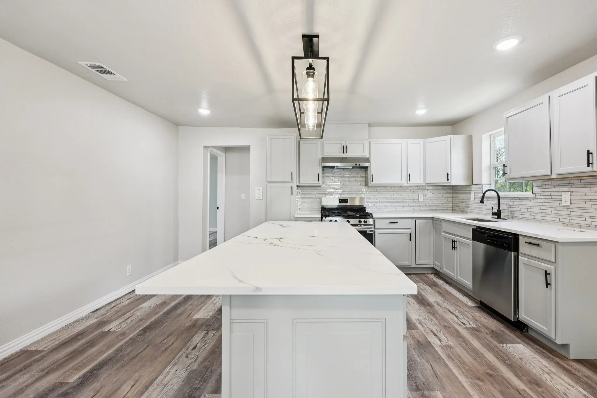 Kitchen featuring an expansive center island with a quartz countertop, wood-finish flooring, recessed lighting, and a contemporary chandelier