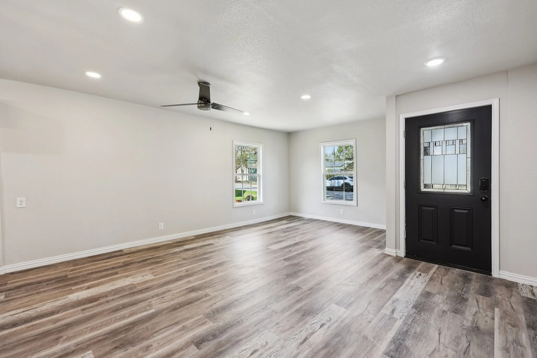 Spacious room featuring wood-finish flooring, recessed lighting, and a contemporary ceiling fan