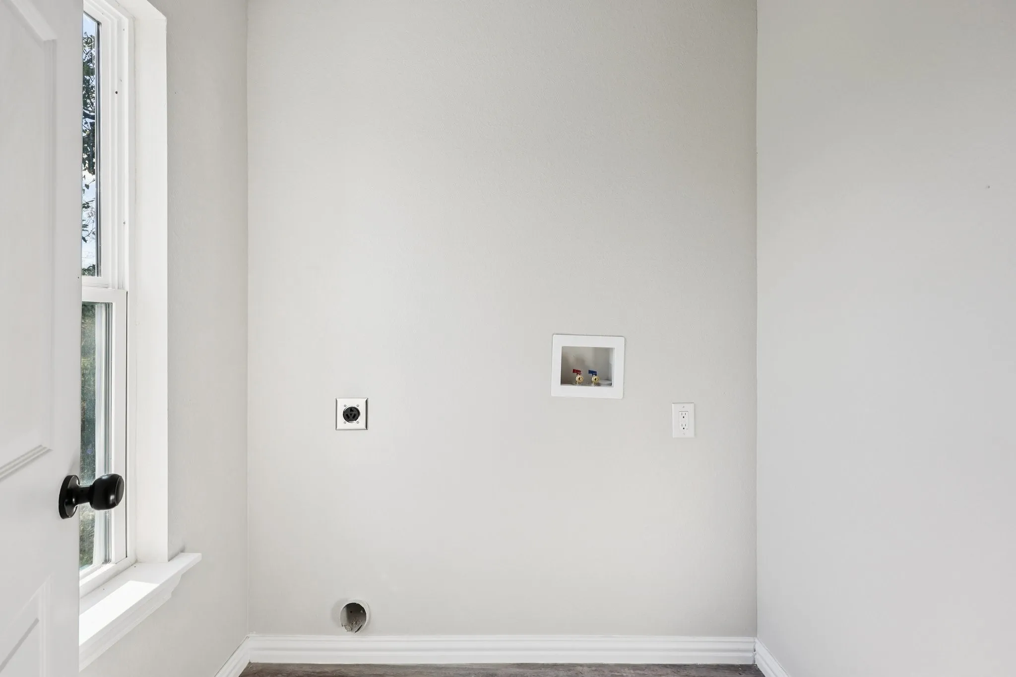Dedicated utility space featuring washer hookups, dryer vent, and electrical outlet
