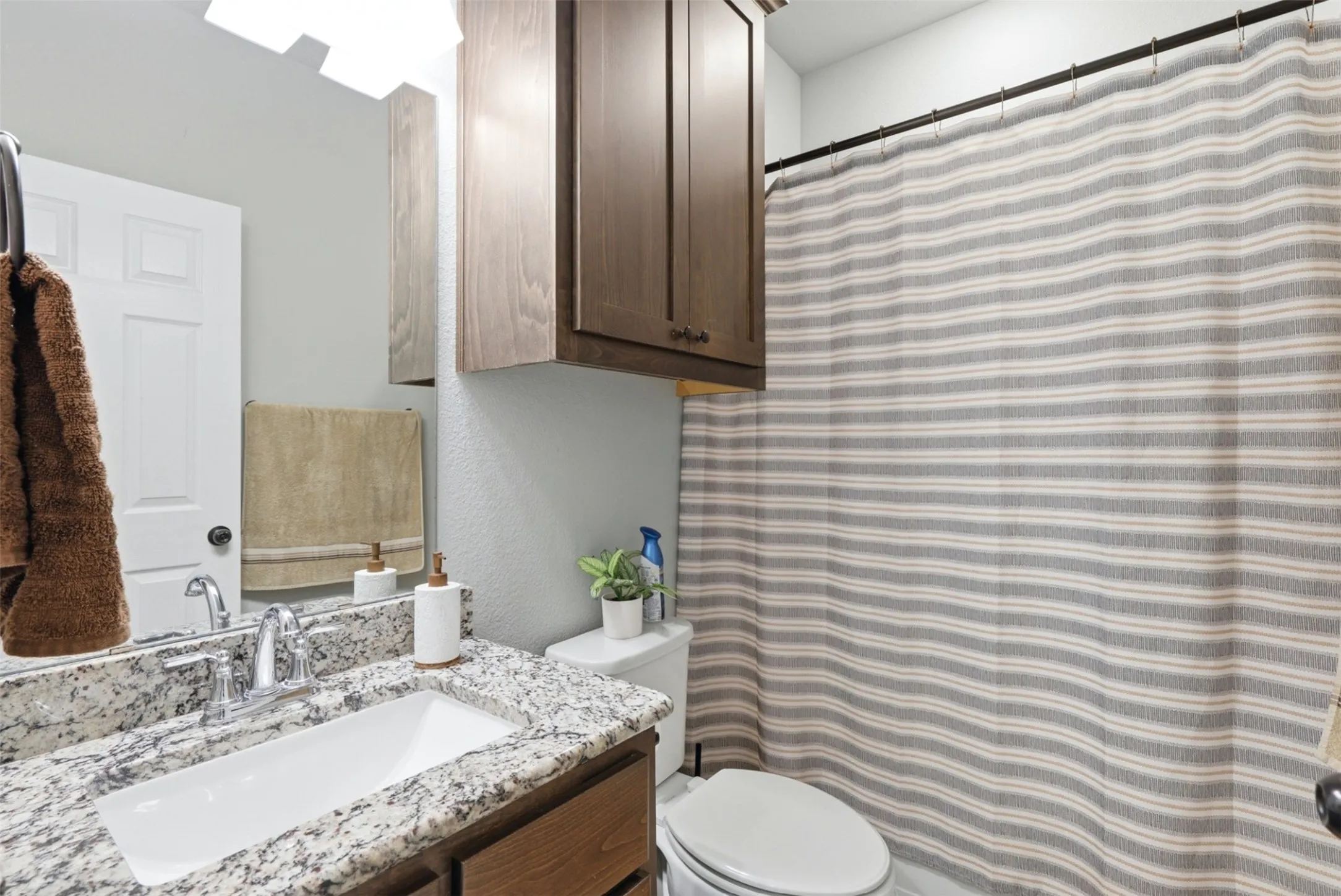 Bathroom vanity featuring a rectangular undermount sink, a stone-finish countertop, and wood-finish cabinetry