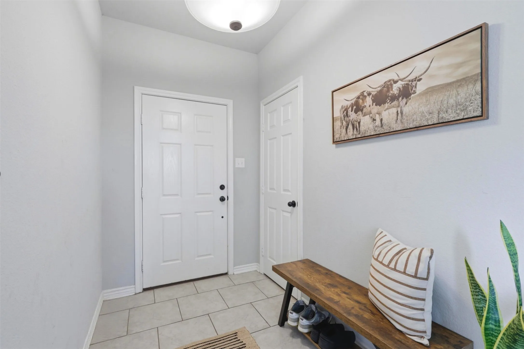 Entryway featuring a paneled door, light gray walls, and ceramic tile flooring