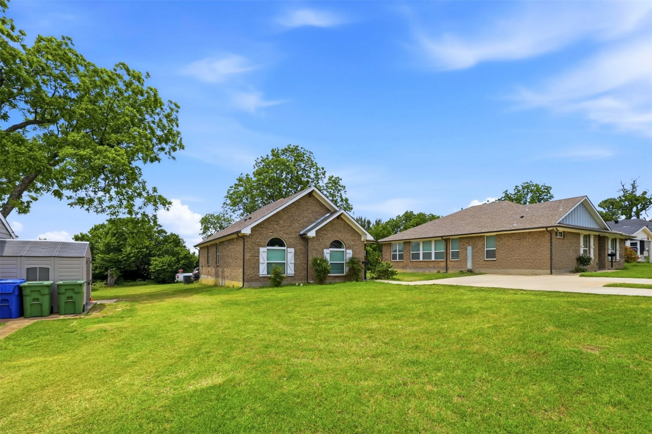Expansive green lawn bordering a brick exterior home with white window shutters