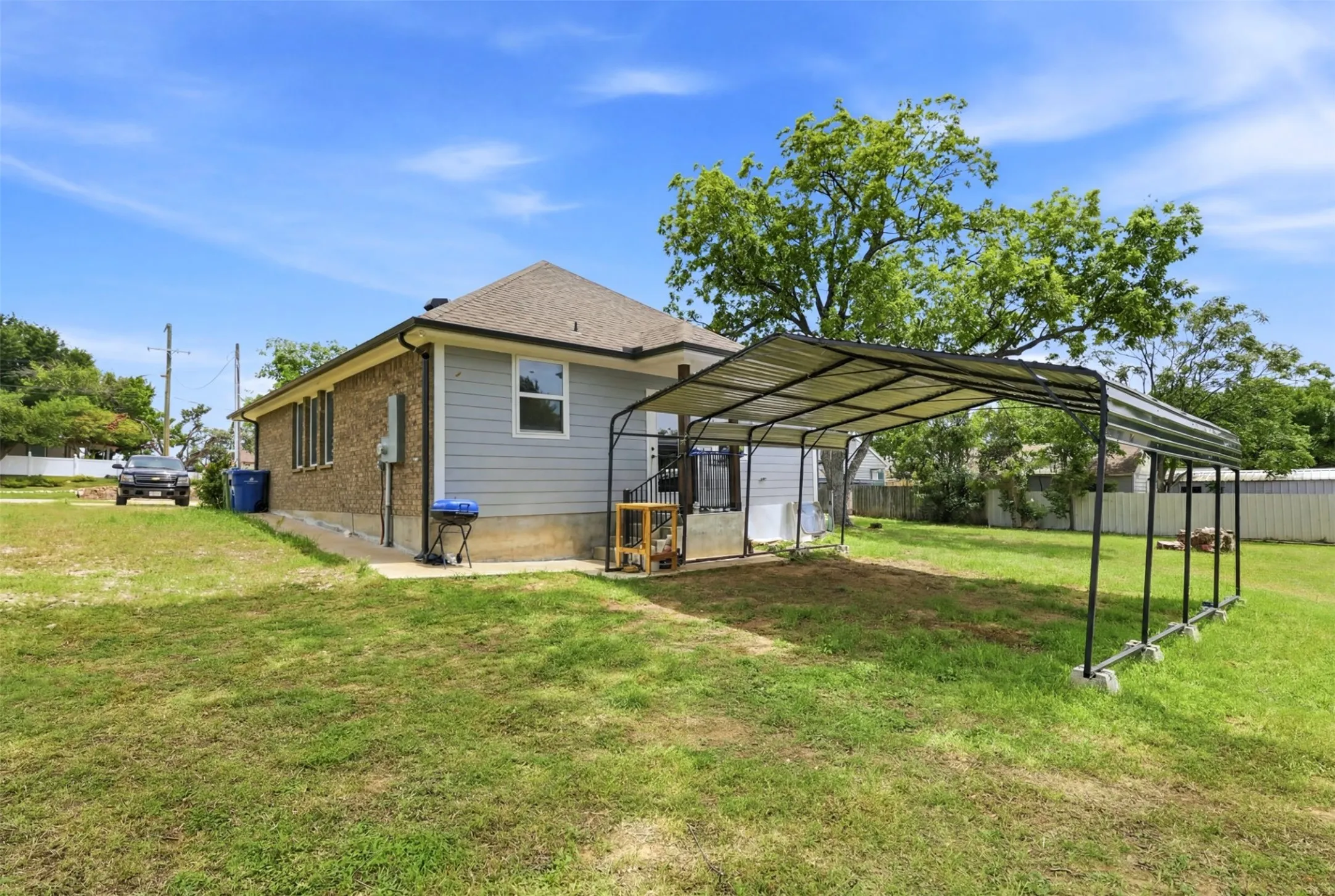 Exterior featuring a metal carport structure, brick and siding facade, and a pitched shingle roof