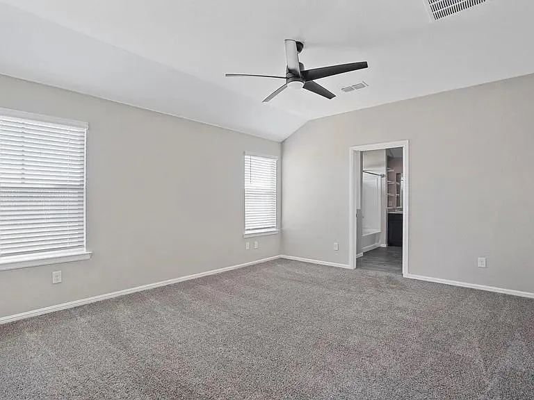 Spacious room featuring vaulted ceilings and a contemporary ceiling fan
