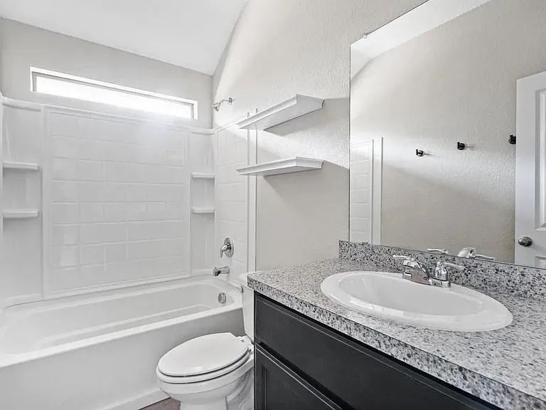 Bathroom featuring a dark wood-finish vanity with a speckled countertop, a white oval undermount sink, and a chrome faucet