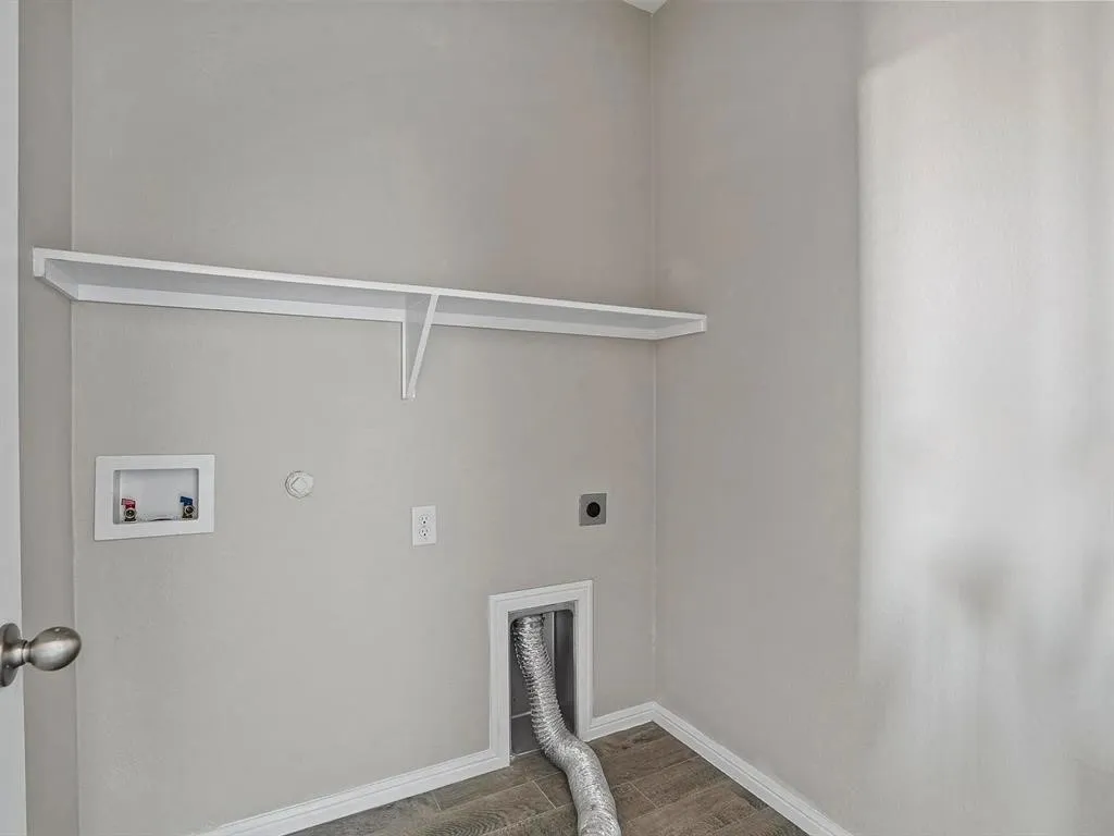 Dedicated utility area with wood-finish flooring, light grey walls, and a white wall-mounted shelf