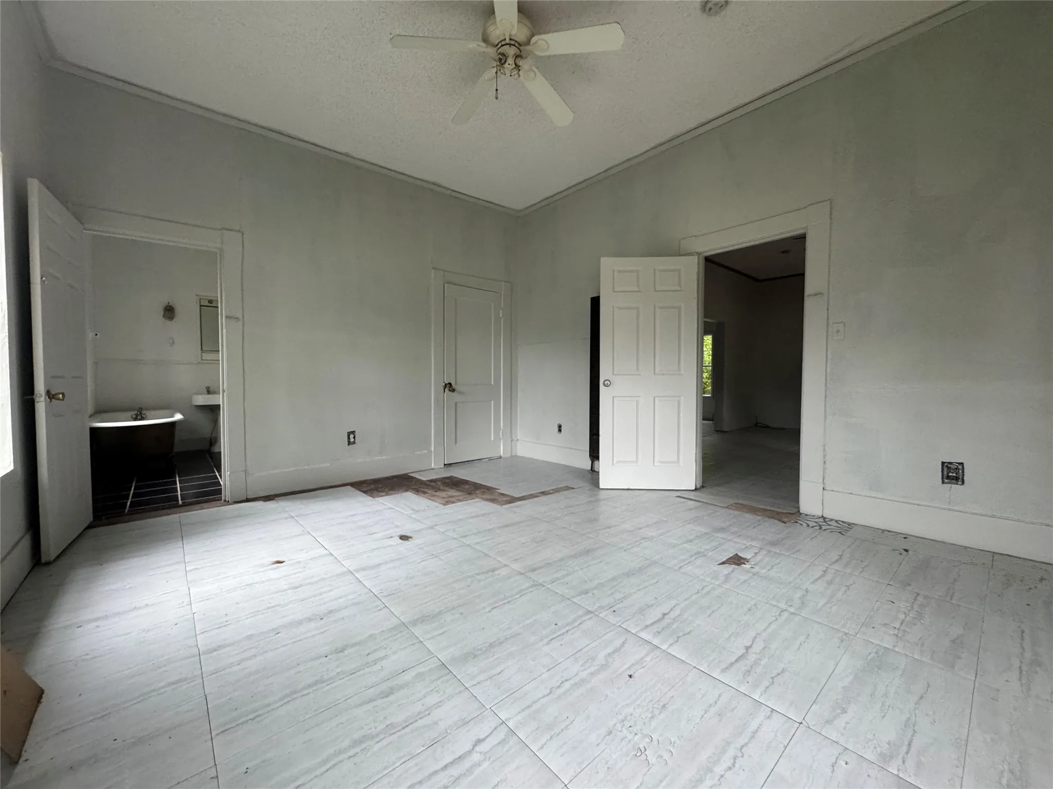 Spacious room featuring light-toned large format floor tiles and a ceiling fan