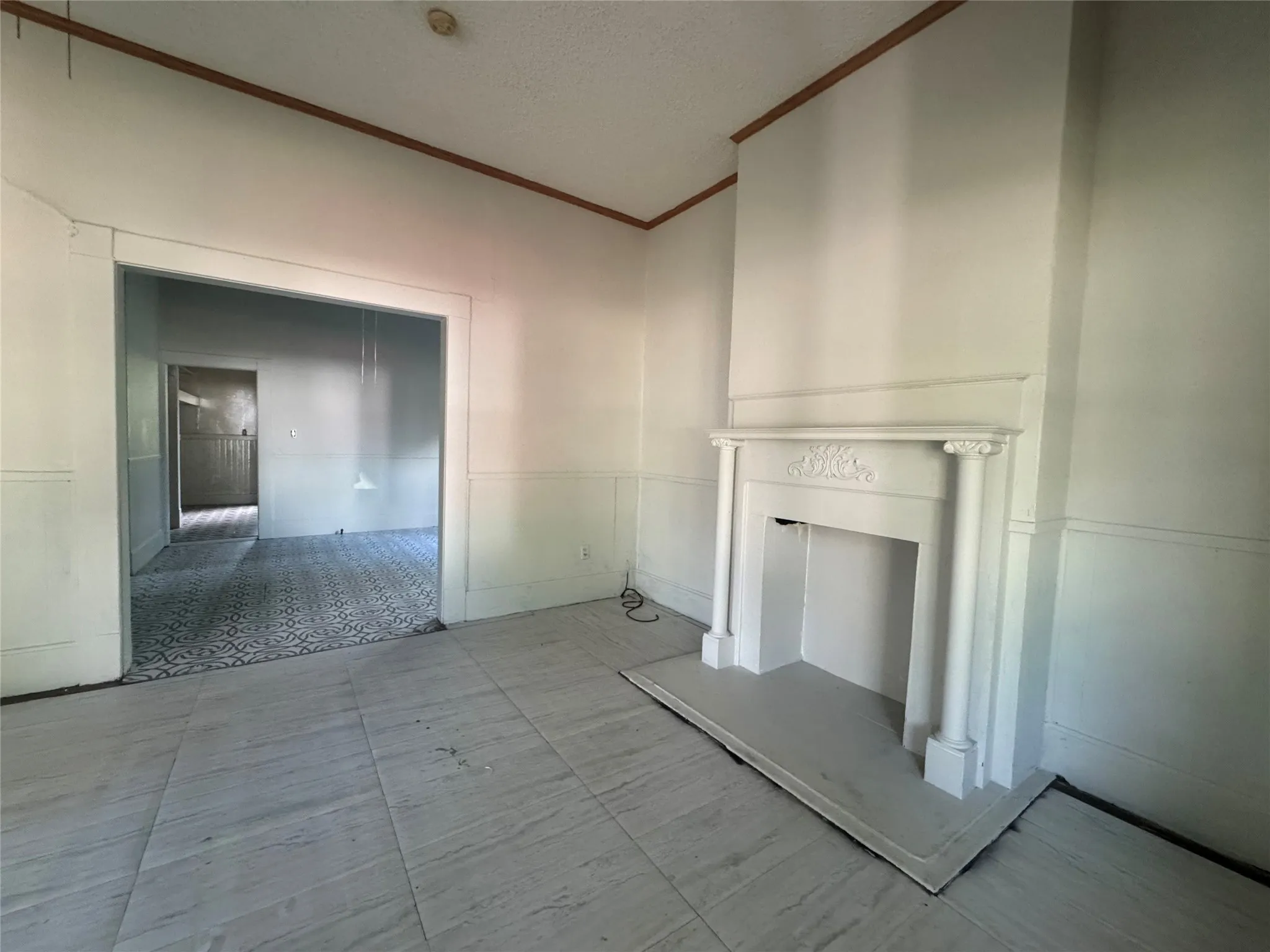 Living area with light-toned plank flooring, wainscoting, and a decorative mantel with fluted columns