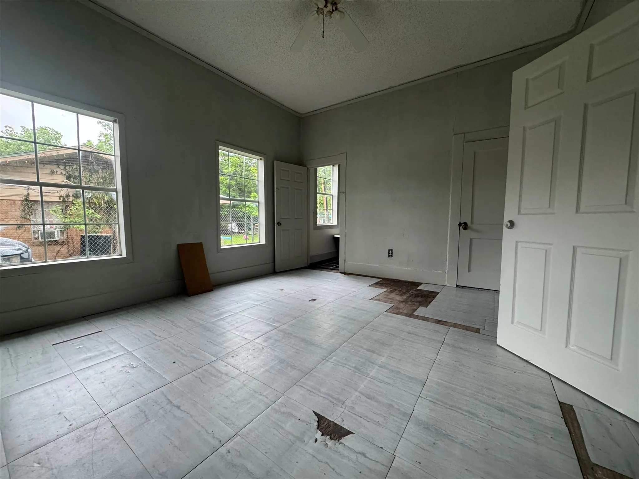 Interior room featuring two large windows with mullions and a ceiling fan